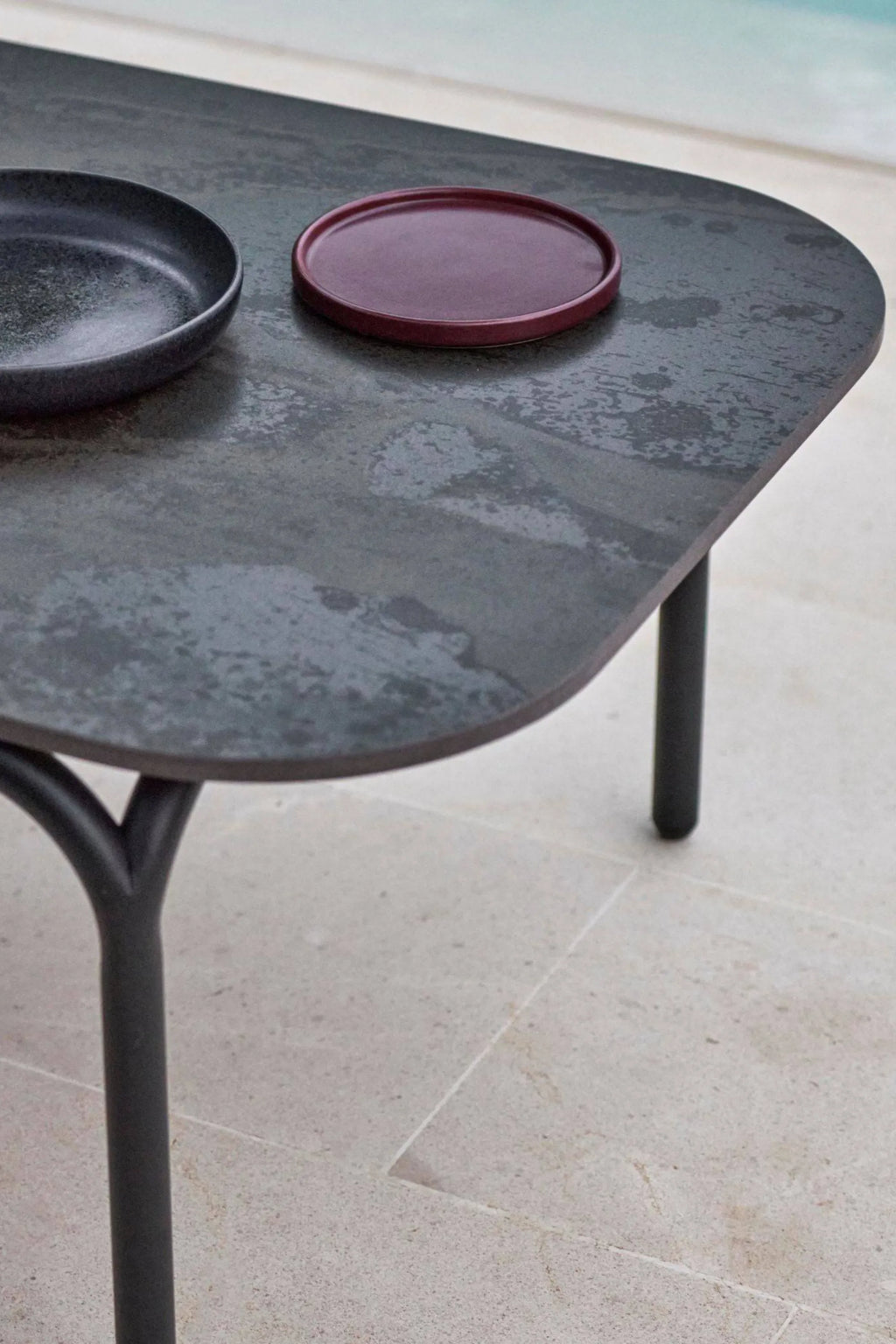 Gandia Blasco Capa Coffee Table, a modern minimalist outdoor coffee table featuring a dark grey ceramic or stone-like tabletop with a textured, mottled finish and rounded rectangular shape, supported by sleek matte black.