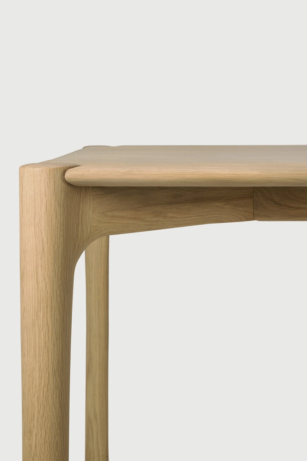 Ethnicraft PI Dining Table, a solid oak dining table showcasing natural wood grain and a warm finish, characterized by its elegantly rounded tabletop corners and thick, organically shaped legs that seamlessly flow into the table's apron. This minimalist and organic modern design makes it an ideal centerpiece for contemporary dining rooms or Scandinavian-inspired kitchens.