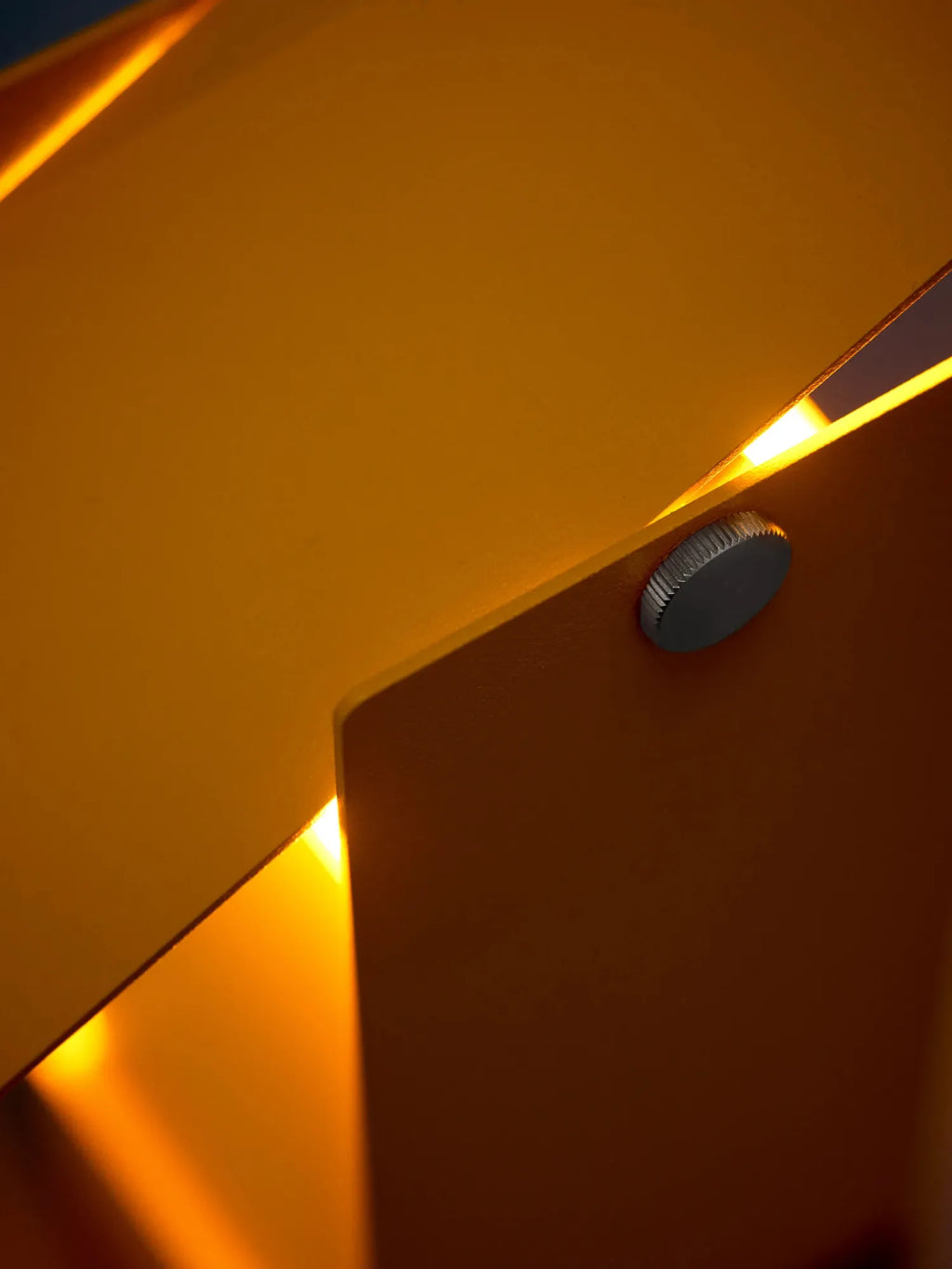 MOEBE Pivoting Table Lamp, a modern minimalist desk lamp crafted from deep mustard yellow matte metal with a striking geometric, folded design and a knurled silver adjustment knob to direct its warm,.