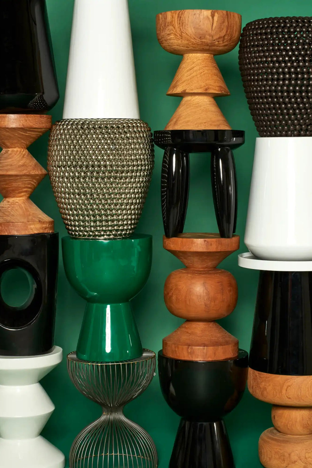 POLSPOTTEN Tip Tap Stool, a striking contemporary sculptural stool known for its modular, stacked geometric forms in a vibrant mix of glossy lacquered finishes and natural wood tones. Featured here are variations in glossy black, glossy white, and emerald green ceramic, alongside warm natural wooden elements and a unique gold metallic textured piece.