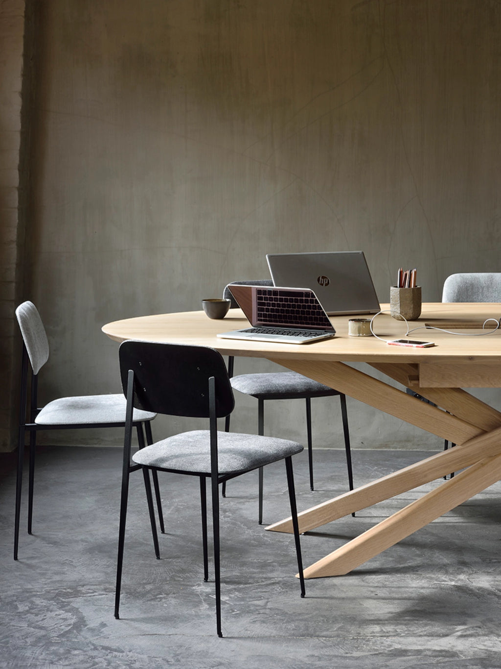 Ethnicraft Mikado Meeting Table, a large oval solid oak dining table with a natural light wood finish and a distinctive interlocking X-shaped base. This modern minimalist conference table offers a spacious surface for contemporary dining rooms or collaborative home office and commercial meeting spaces.