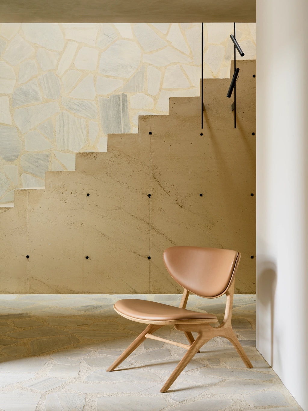 Ethnicraft Eye Lounge Chair, a striking organic modern lounge chair featuring a sculptural solid wood frame in a light natural finish and a beautifully curved backrest and seat upholstered in smooth tan leather. Its minimalist design and low-slung profile make it an ideal accent chair for contemporary living rooms, reading nooks, or sophisticated Scandinavian-inspired spaces.