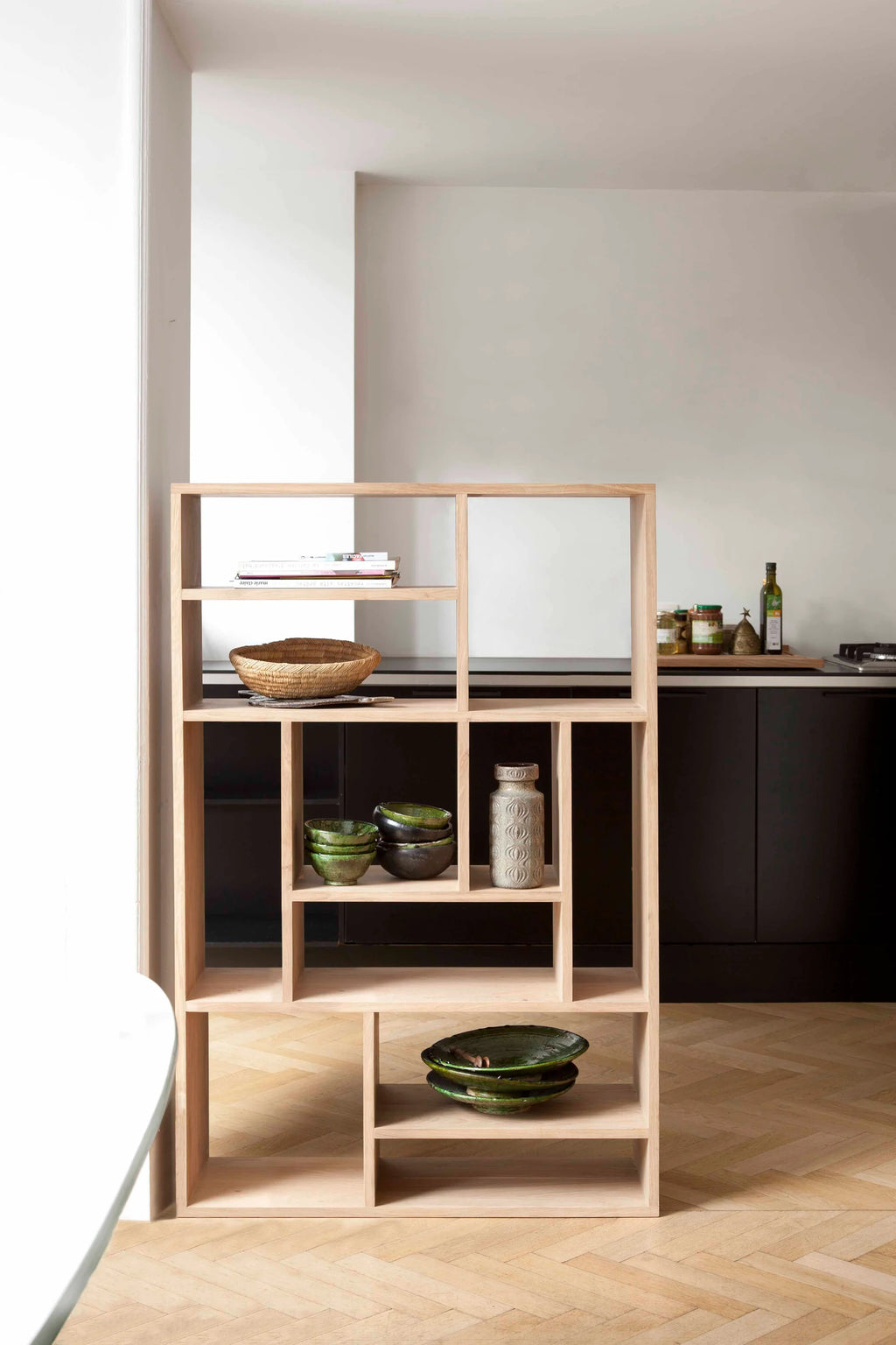 Ethnicraft M Rack, a modern minimalist shelving unit crafted from light natural solid oak wood, featuring an innovative asymmetrical design with varied open cubbies and clean lines. This versatile oak bookcase is perfect for Scandinavian or Japandi interiors, serving as a stylish display shelf for living rooms, dining areas, or home offices.