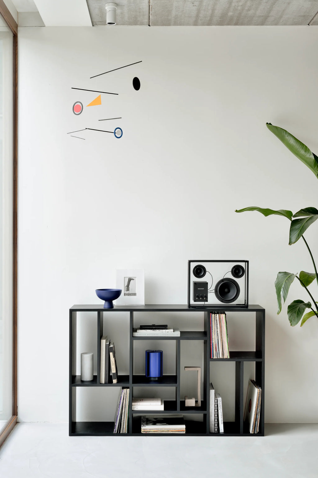 Ethnicraft M Rack, a modern minimalist shelving unit crafted from black stained solid oak with a sleek matte finish and varied open compartments, creating a striking geometric design. This contemporary bookcase is perfect for stylish living room storage, media display, or organizing vinyl records in industrial chic or Scandinavian homes.