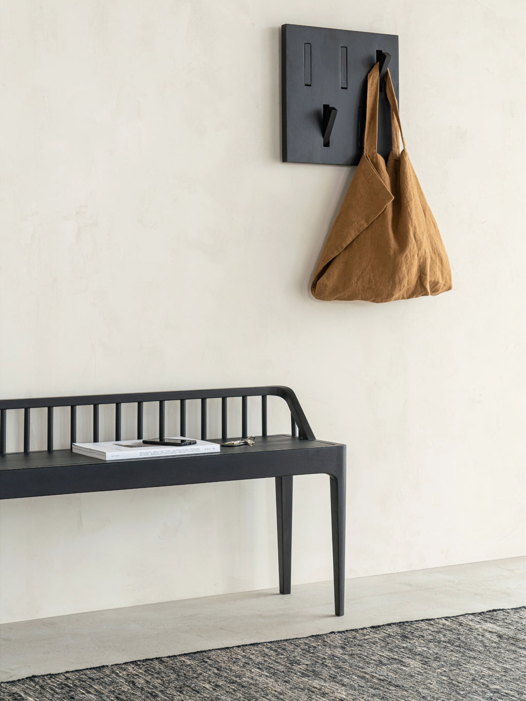 Ethnicraft Spindle Bench, a sleek modern minimalist bench crafted from solid black varnished oak with a distinctive slatted backrest and elegantly tapered legs, embodying classic Scandinavian design. This versatile black wood bench is perfect as a stylish entryway console, a contemporary dining bench, or an accent piece for organic modern living rooms and hallways.