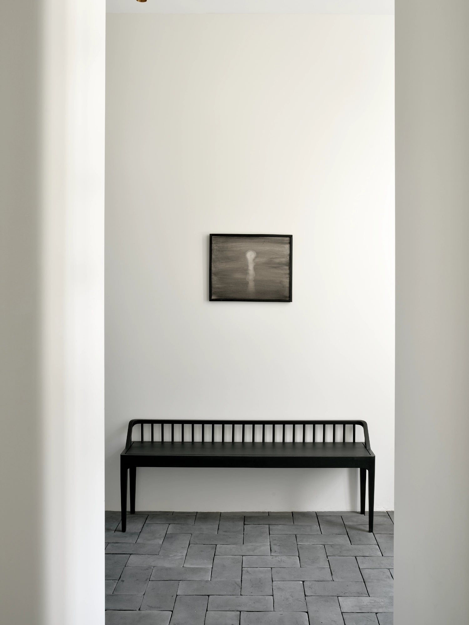 Ethnicraft Spindle Bench, a sleek matte black solid wood bench featuring a distinctive vertical spindle backrest, clean lines, and elegantly tapered legs. This modern minimalist wooden bench is perfect for a Scandinavian entryway, contemporary hallway, or as stylish dining seating.