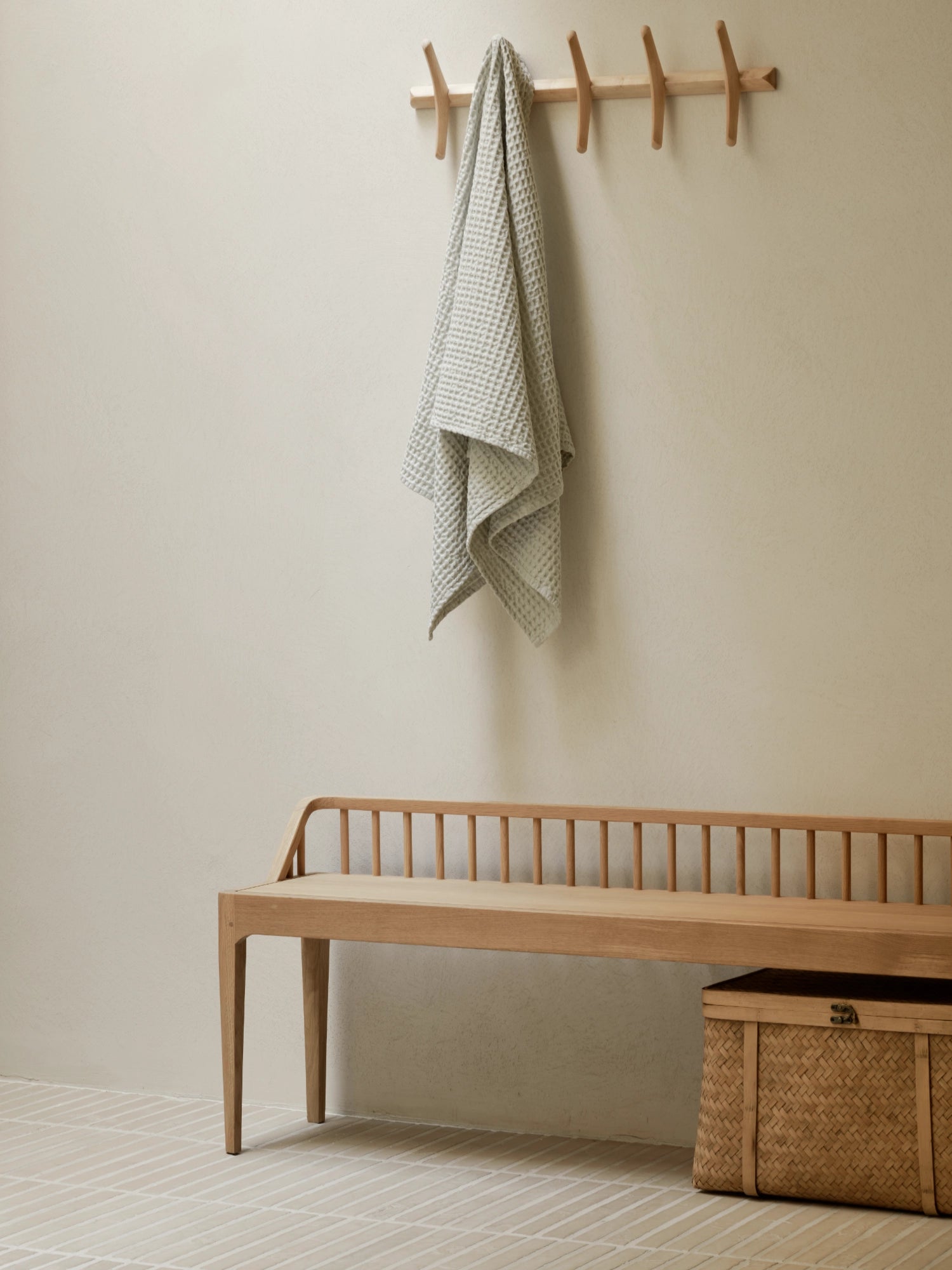 Ethnicraft Spindle Bench, a modern minimalist solid oak bench featuring a distinctive spindle backrest, gracefully curved armrests, and elegant tapered legs in a warm, light natural wood finish.