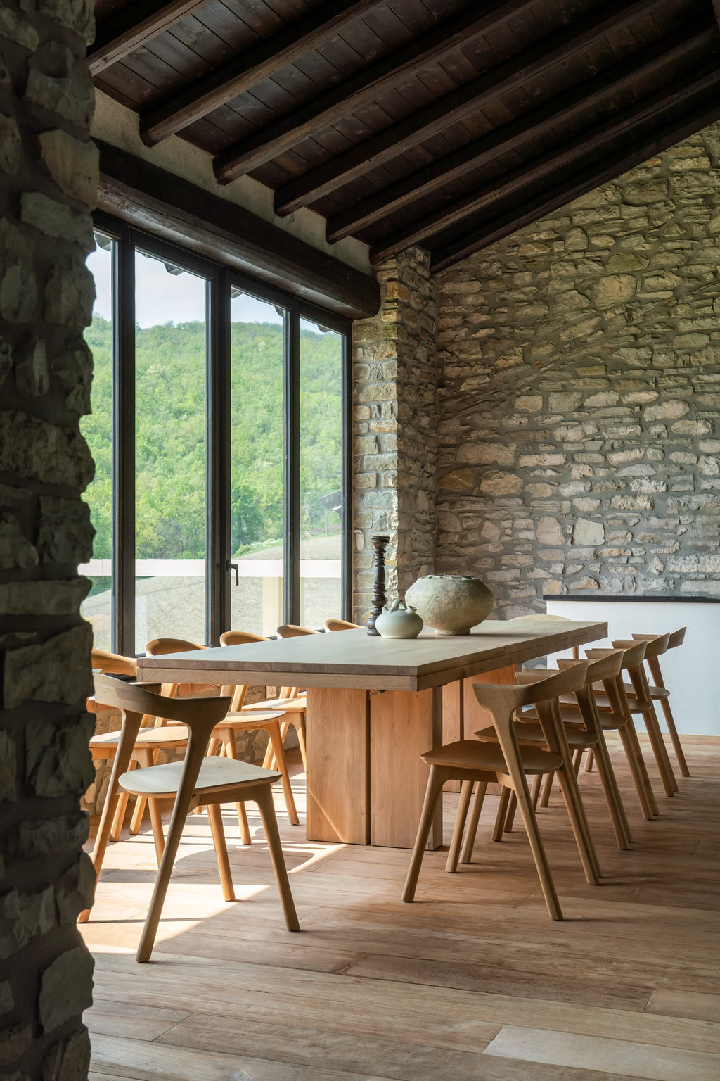 Ethnicraft Double Extendable Dining Table, a large, rectangular solid oak dining table in a light natural finish, featuring a robust, minimalist design with thick panel legs and a smooth wooden surface. This modern extendable dining table is crafted for versatility and durable use. Perfect for Scandinavian or organic modern dining rooms, ideal for large gatherings and everyday family meals.