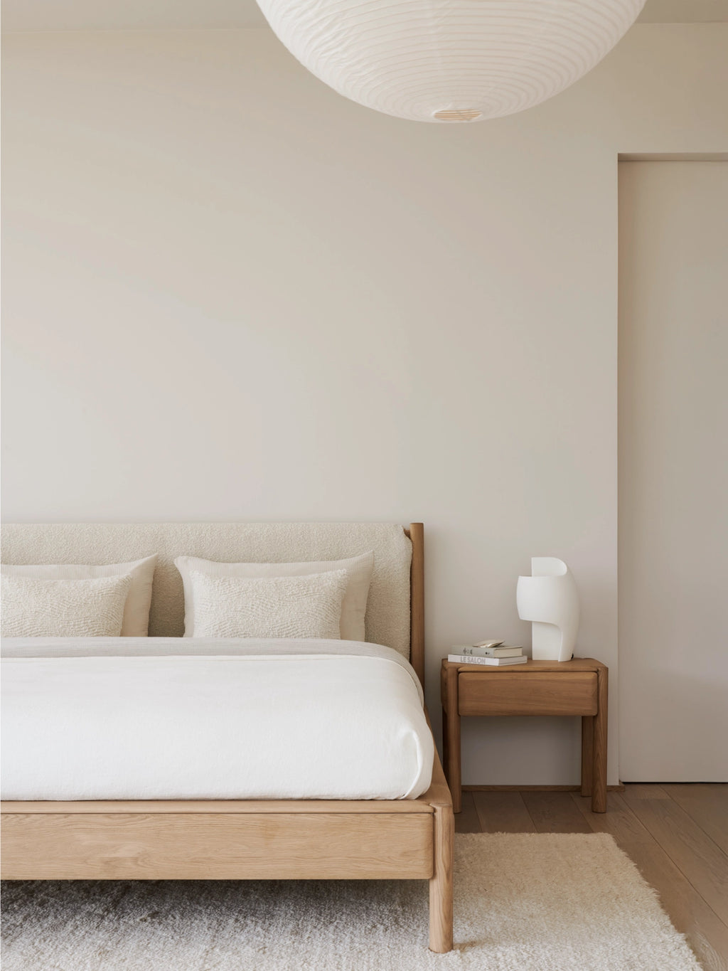 Ethnicraft PI Bedside Table, a modern minimalist nightstand crafted from solid natural light oak wood with visible grain and a warm, smooth finish. This contemporary bedside table features a single integrated drawer for discreet storage and four sturdy, clean-lined legs. Ideal for Scandinavian bedrooms, organic modern spaces, or minimalist guest rooms seeking elegant wooden furniture.
