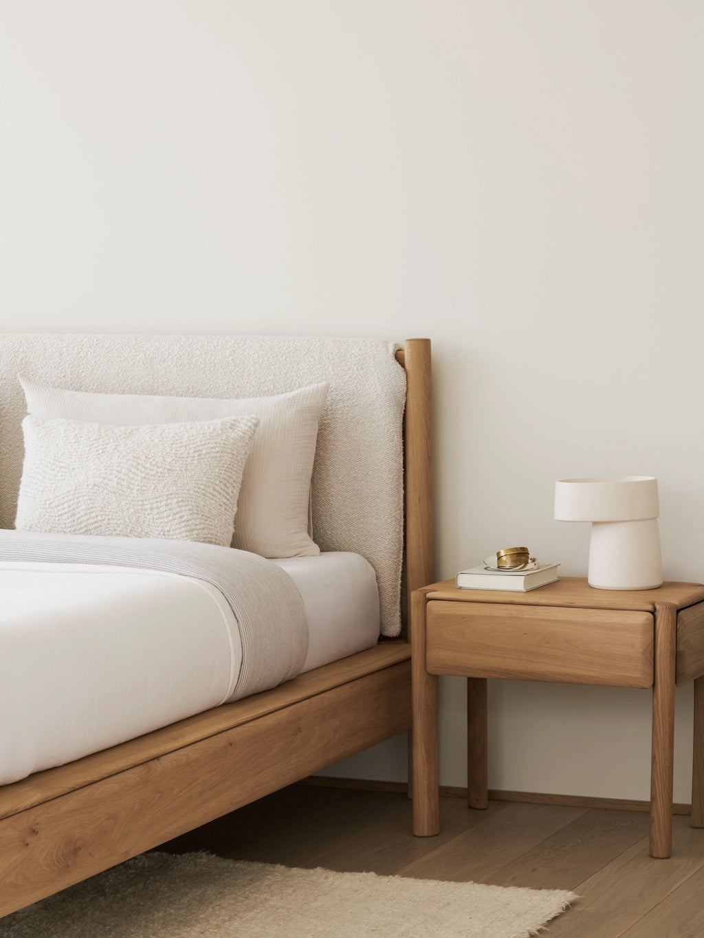 Ethnicraft PI Bedside Table, a modern minimalist solid oak nightstand crafted from natural light wood with a smooth grain finish, featuring a single spacious drawer and subtly rounded legs. This elegant piece is perfect for Scandinavian bedrooms or contemporary organic modern interiors needing sophisticated bedside storage.