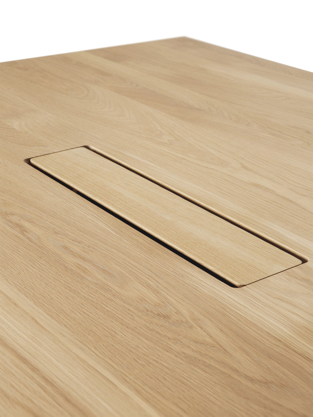 Ethnicraft Geometric Meeting Table, a modern minimalist dining or meeting table crafted from light natural solid oak wood, showcasing a smooth grain texture. It features an integrated rectangular recessed compartment for discreet cable management, blending seamlessly into the blonde oak tabletop. This contemporary oak table is ideal for Scandinavian dining rooms, modern home offices, or professional conference spaces.