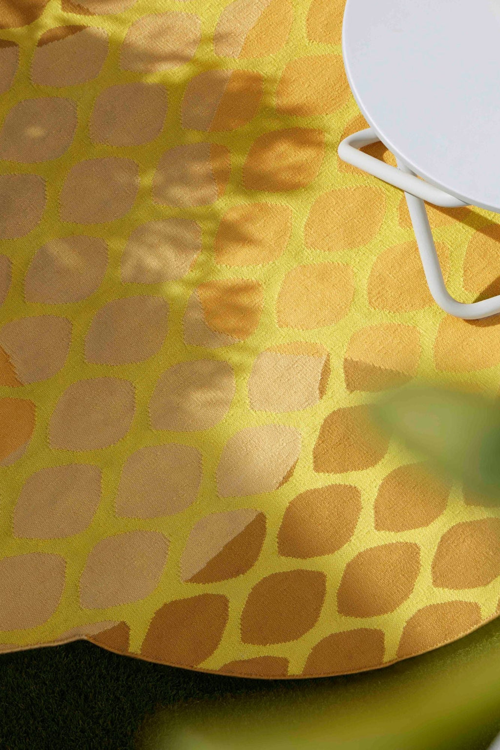 GAN Rugs Citrus Outdoor Rug, a vibrant round woven outdoor rug featuring a bold graphic pattern of overlapping oval shapes in bright yellow and warm orange tones. The durable, weather-resistant textile is designed to withstand outdoor elements. Perfect for adding a playful, contemporary touch to a patio, deck, or outdoor living space.