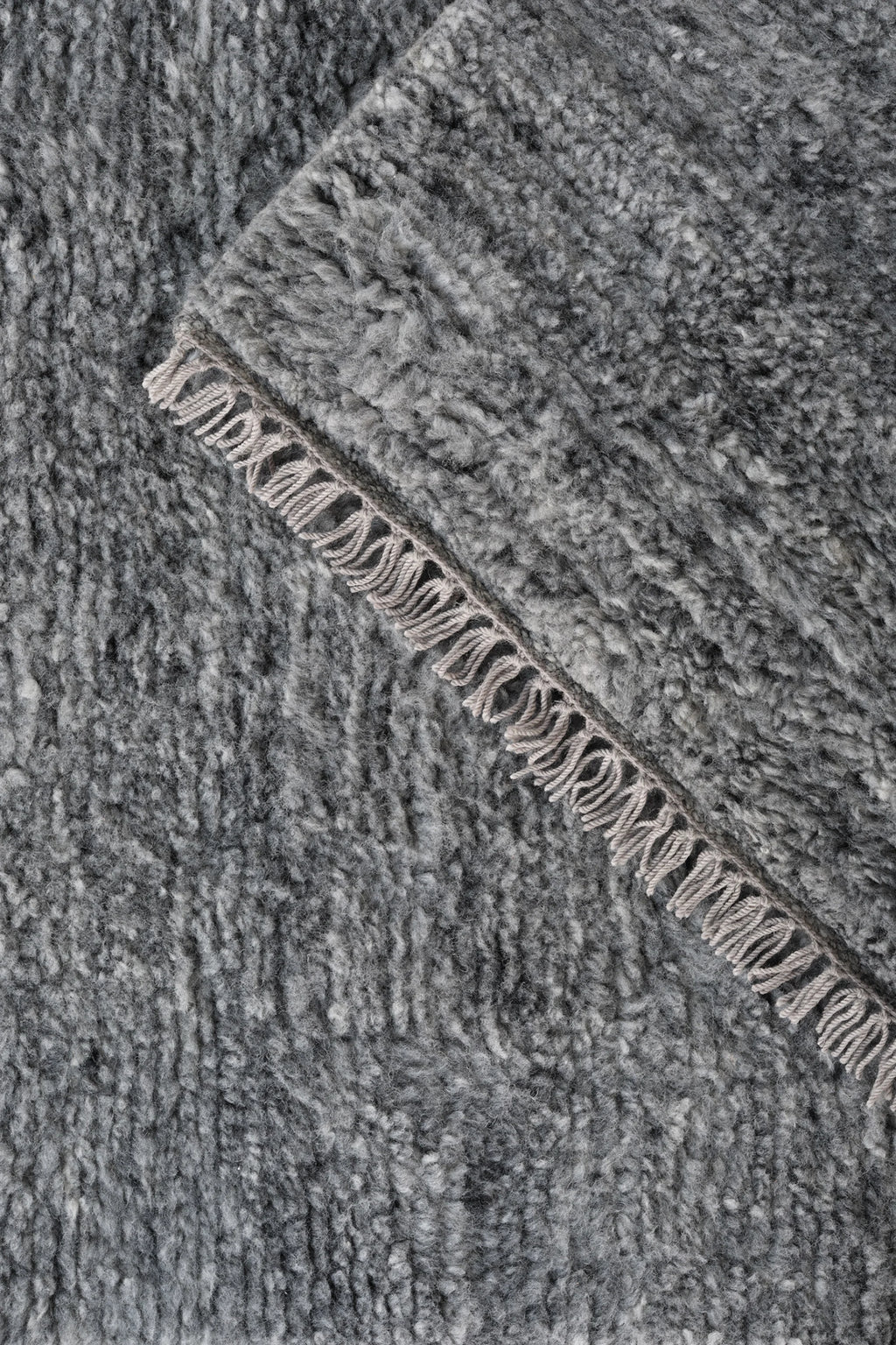 Linie Design Soft Savannah Wool Rug, a luxurious hand-knotted wool area rug featuring a deep, heathered grey pile with a soft, shaggy texture and a subtly fringed edge. This contemporary grey rug provides exceptional warmth and comfort, ideal for adding an organic modern touch to Scandinavian living rooms, cozy bedrooms, or minimalist interiors.