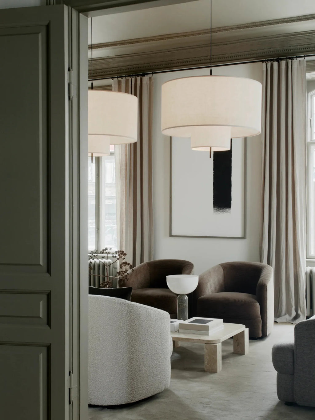 New Works Margin Pendant Lamp, featuring a layered, cream fabric drum shade in a modern living room setting. This designer ceiling light exudes premium sophistication. Ideal for ambient lighting.