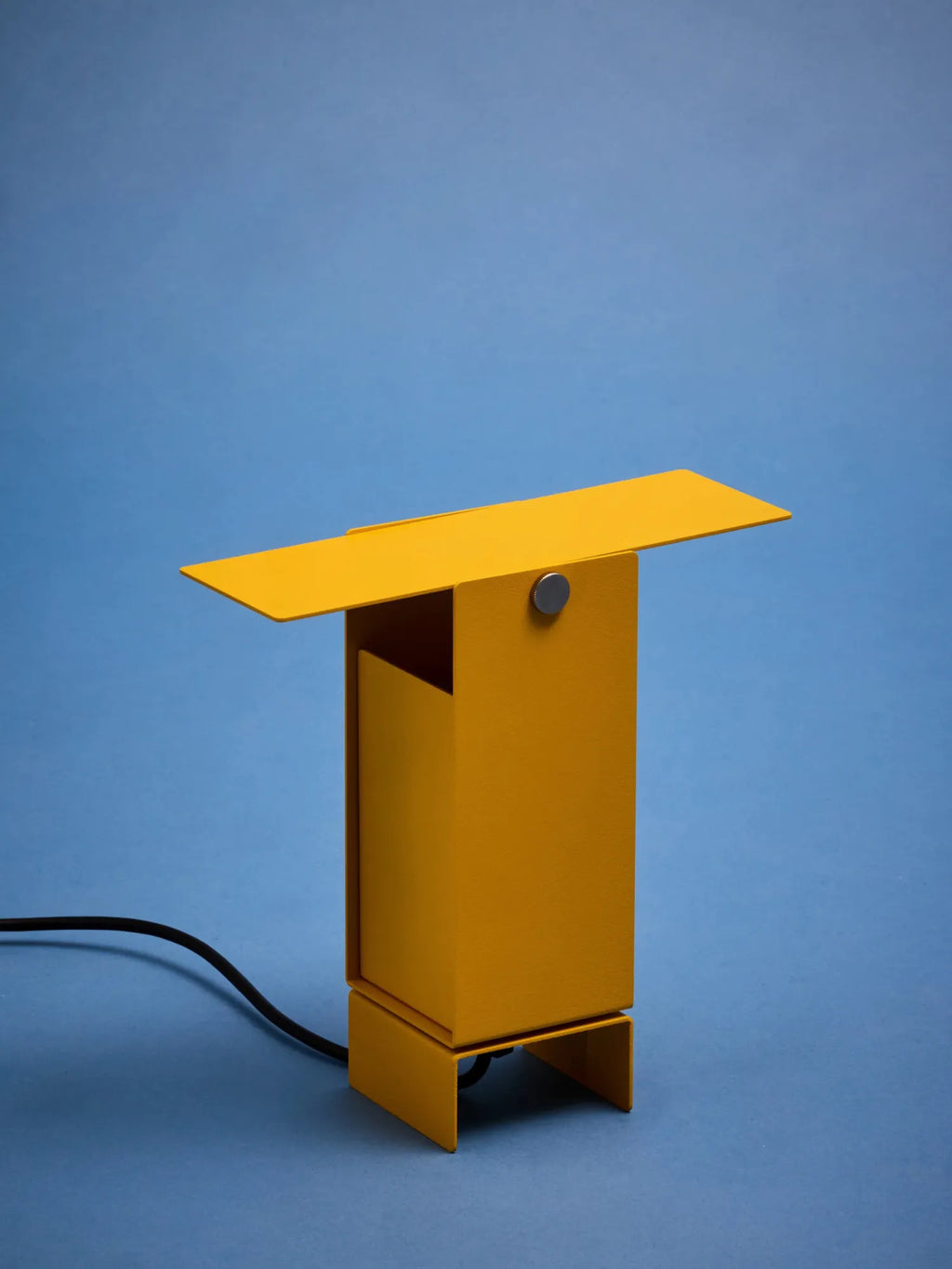 MOEBE Pivoting Table Lamp, a modern minimalist desk lamp featuring a bold matte mustard yellow powder-coated steel construction with a sleek rectangular base and an adjustable pivoting rectangular shade, accented by a subtle brushed silver pivot mechanism. This industrial chic table lamp provides focused directional light, perfect for contemporary home office desks, creative studio spaces, or as a vibrant accent for modern living rooms.