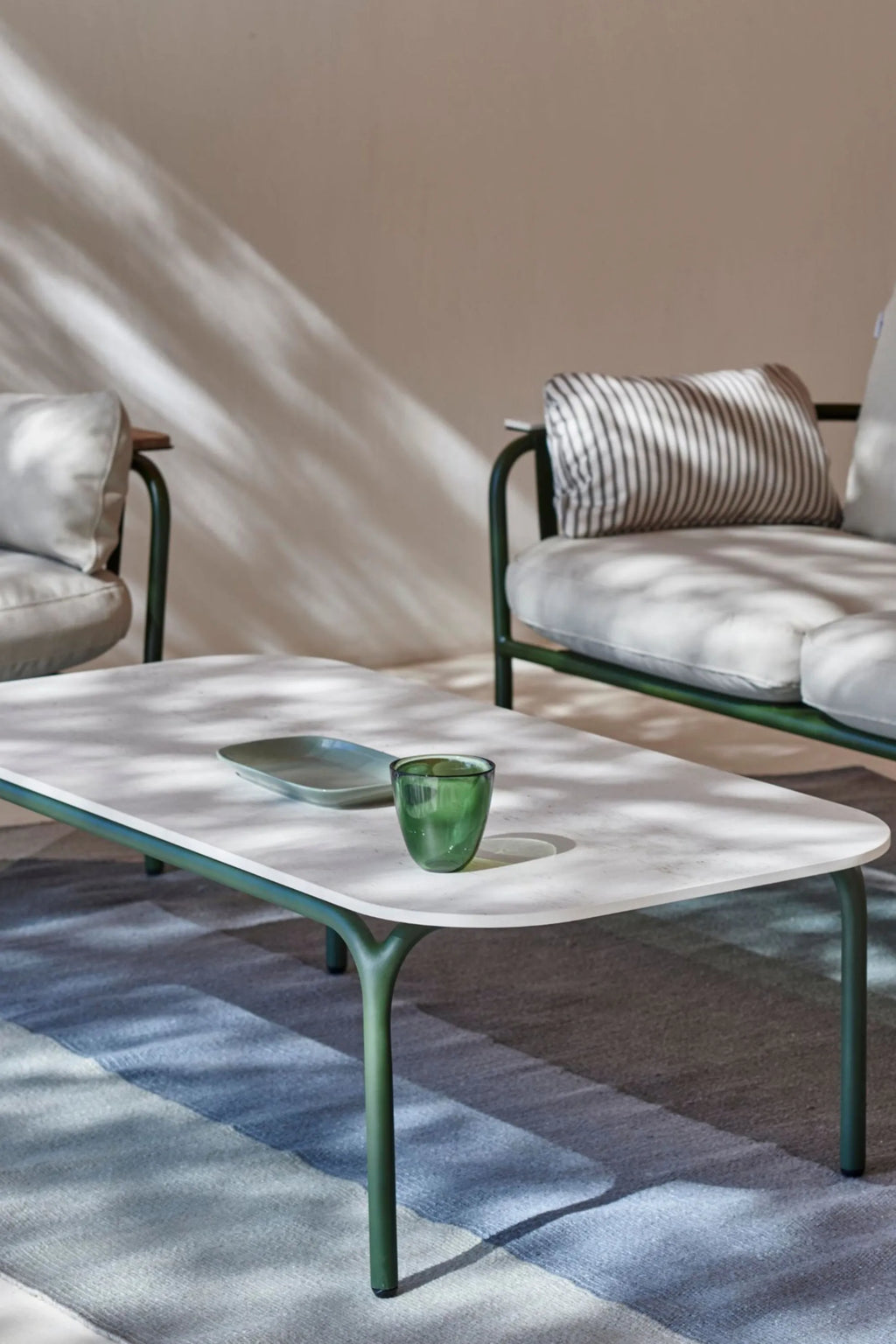 Gandia Blasco Capa Coffee Table, a modern outdoor coffee table featuring a rectangular light grey stone-effect tabletop with soft rounded corners, supported by elegant dark green matte metal legs with a subtly curved design. This contemporary outdoor table is perfect for minimalist patio spaces, terraces, or garden lounging areas.
