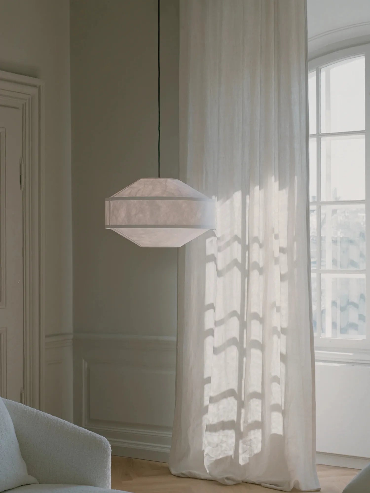 New Works Kite Pendant Lamp featuring a unique octagonal natural white rice paper shade and black cord, elegantly suspended in a sunlit modern interior. Perfect for creating ambient, decorative lighting.