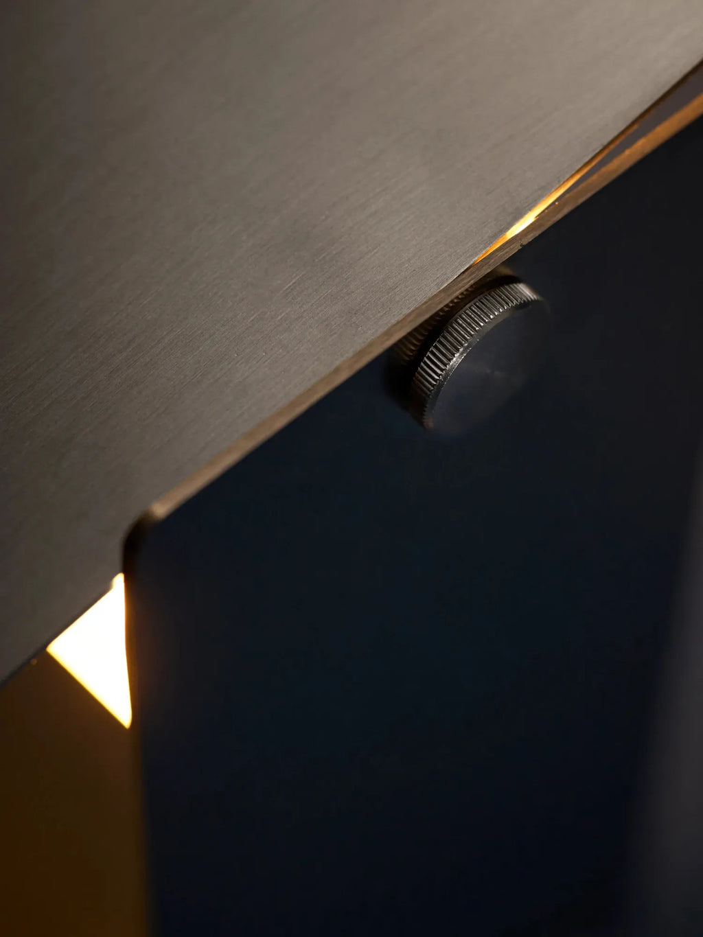 MOEBE Pivoting Table Lamp, a modern minimalist desk lamp crafted from dark grey brushed metal with a distinctive knurled adjustment knob, directing warm LED light from its slender, pivoting head. This industrial chic lamp is perfect for contemporary home office lighting, Scandinavian workspaces, or as a sophisticated bedside table accent.