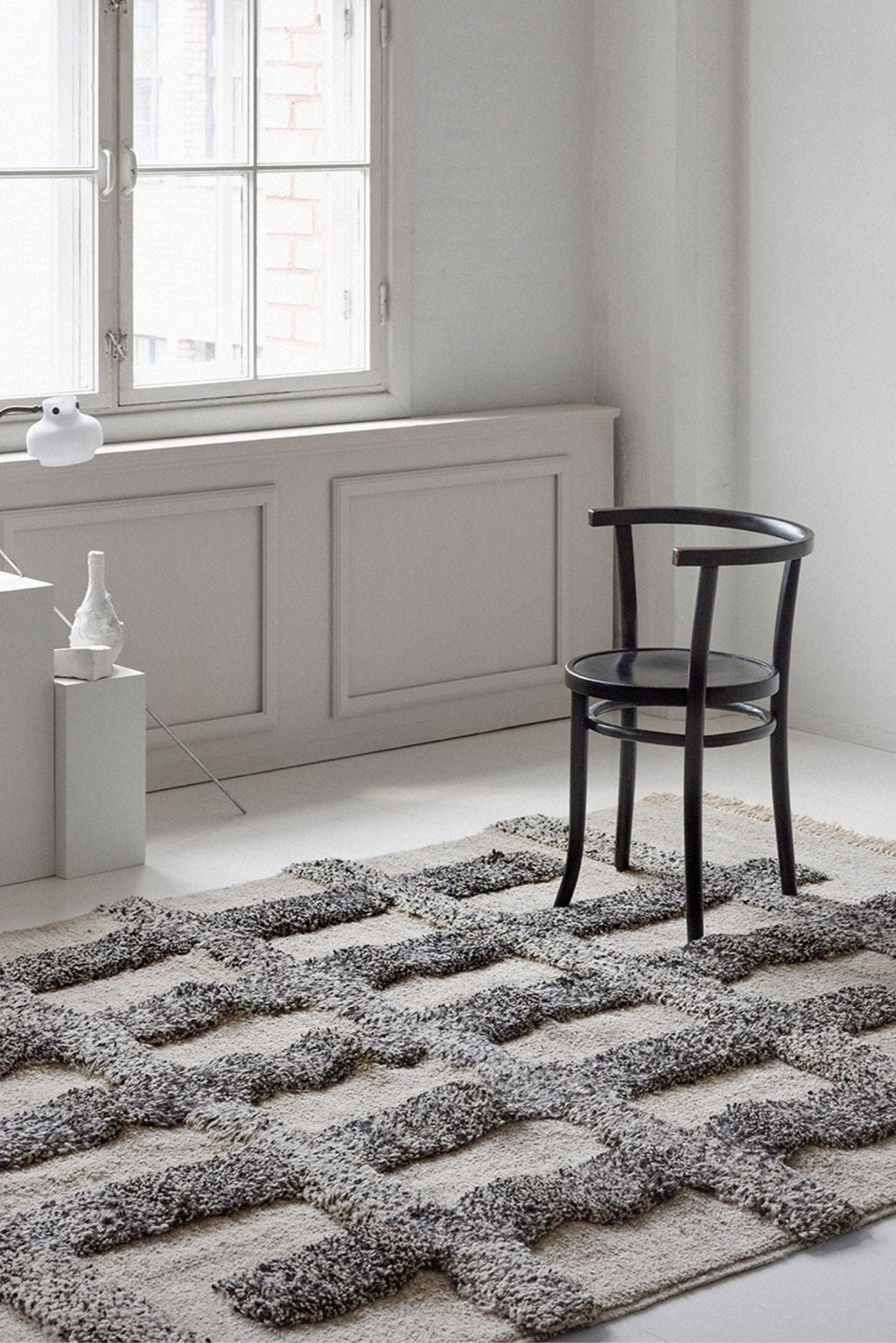 Sera Helsinki Valli Wool Rug, a hand-knotted wool area rug featuring a high-low pile with a natural cream base and raised, textured grey geometric patterns. This Scandinavian-inspired design offers a cozy feel and an organic modern aesthetic for contemporary interiors. Ideal for minimalist living rooms, bedrooms, or cozy reading nooks.