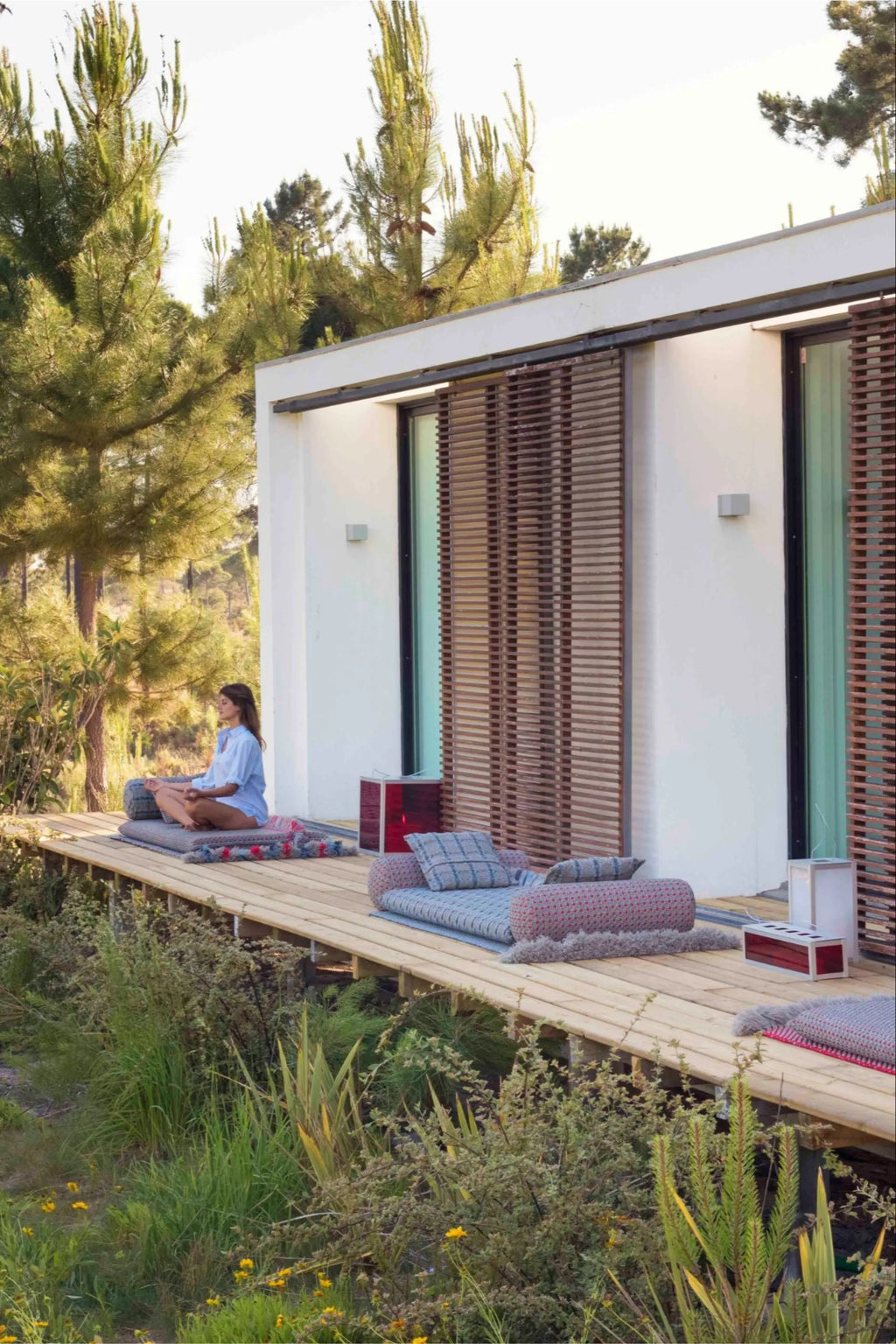 GAN Rugs Garden Layers Composition 05, a modular outdoor sofa featuring weather-resistant fabric mattresses, cylindrical bolsters, and square cushions in muted blue, grey, and reddish-pink woven patterns with plush fringed edges. This organic modern outdoor lounge seating creates a relaxed, contemporary outdoor living space perfect for patios, decks, or garden retreats.