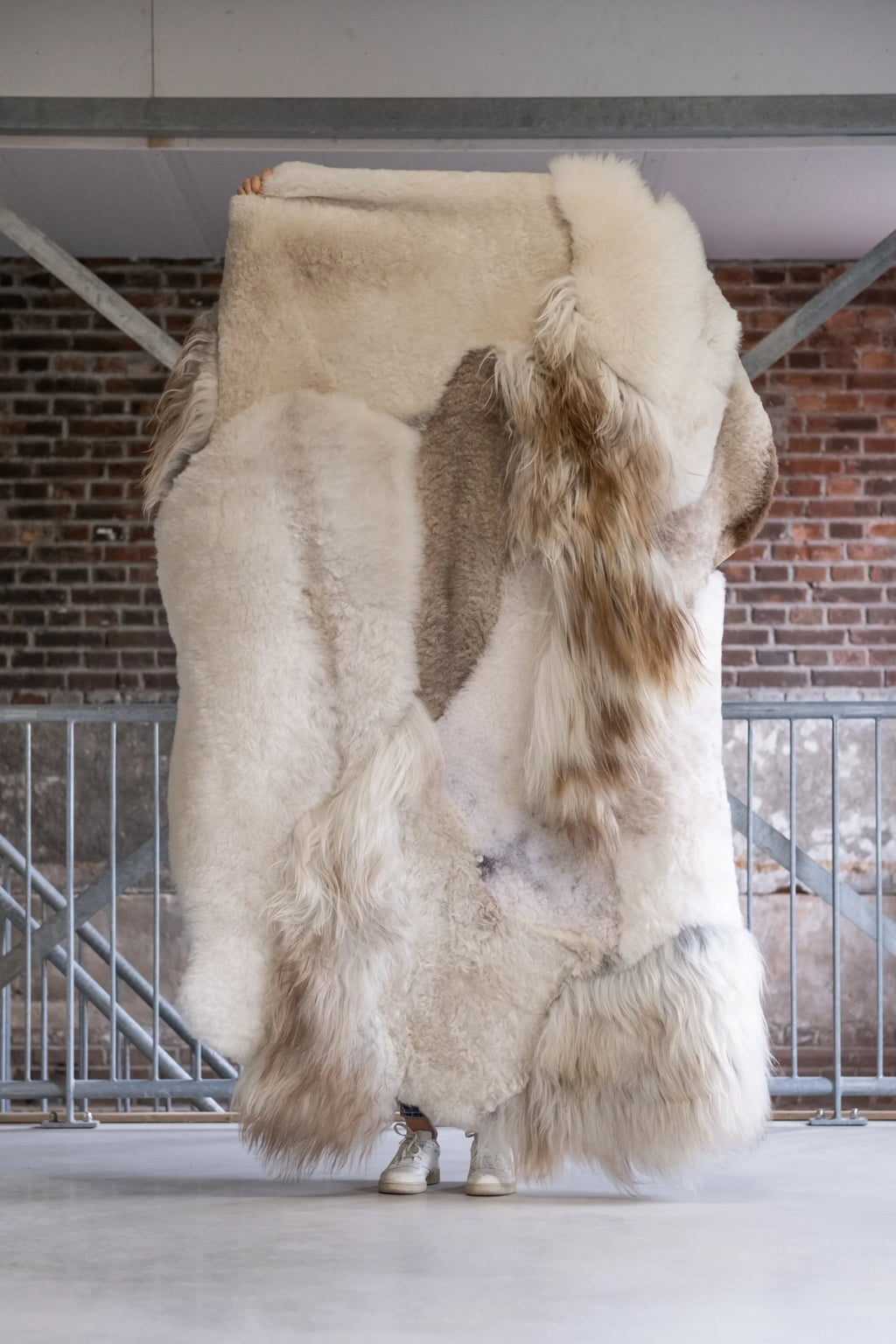Large fur coat displayed against a brick wall.