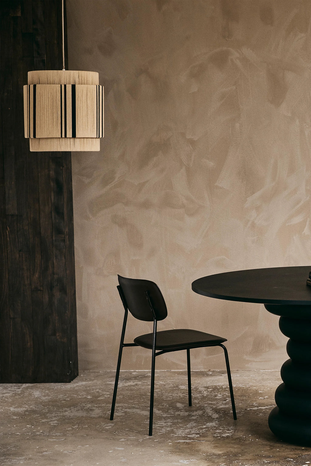 Nordal Yalu Dining Table, a striking matte black round dining table with a distinctive sculptural base composed of stacked, organic forms, crafted for a contemporary and organic modern aesthetic.