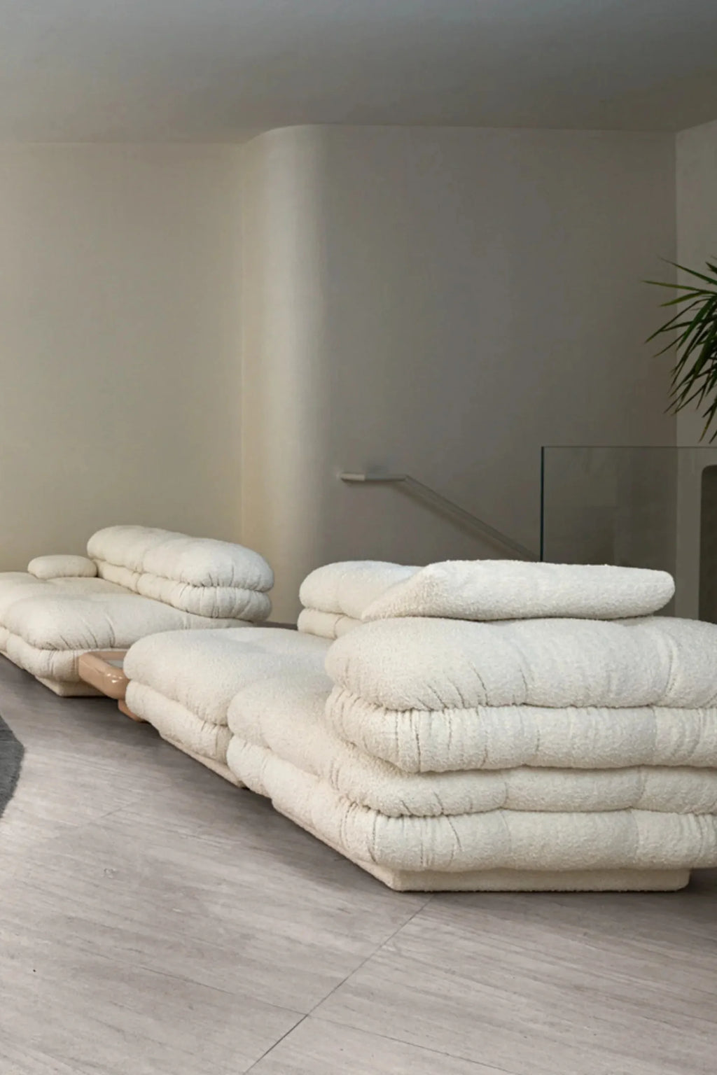 Hessentia Lowell Modular Sofa, an inviting cream bouclé modular sofa featuring plush, deep-seated cushions with a soft, textured fabric upholstery and a subtle light wood base. Its low-profile, organic modern design creates a cloud-like aesthetic, ideal for flexible arrangements in contemporary living rooms and luxurious minimalist lounge areas.