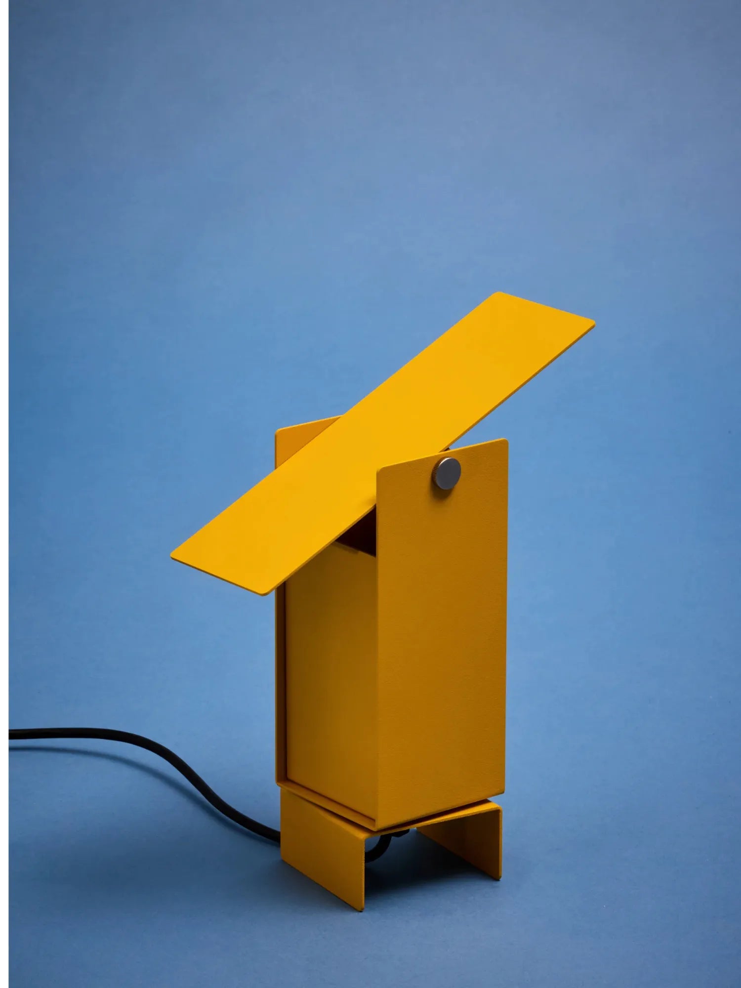 MOEBE Pivoting Table Lamp, a vibrant matte yellow powder-coated steel table lamp with a geometric, minimalist design, featuring a rectangular pivoting shade and base for adjustable task lighting. This contemporary industrial-style desk lamp offers functional illumination, perfect for a modern home office, creative workspace, or as a striking bedside accent.