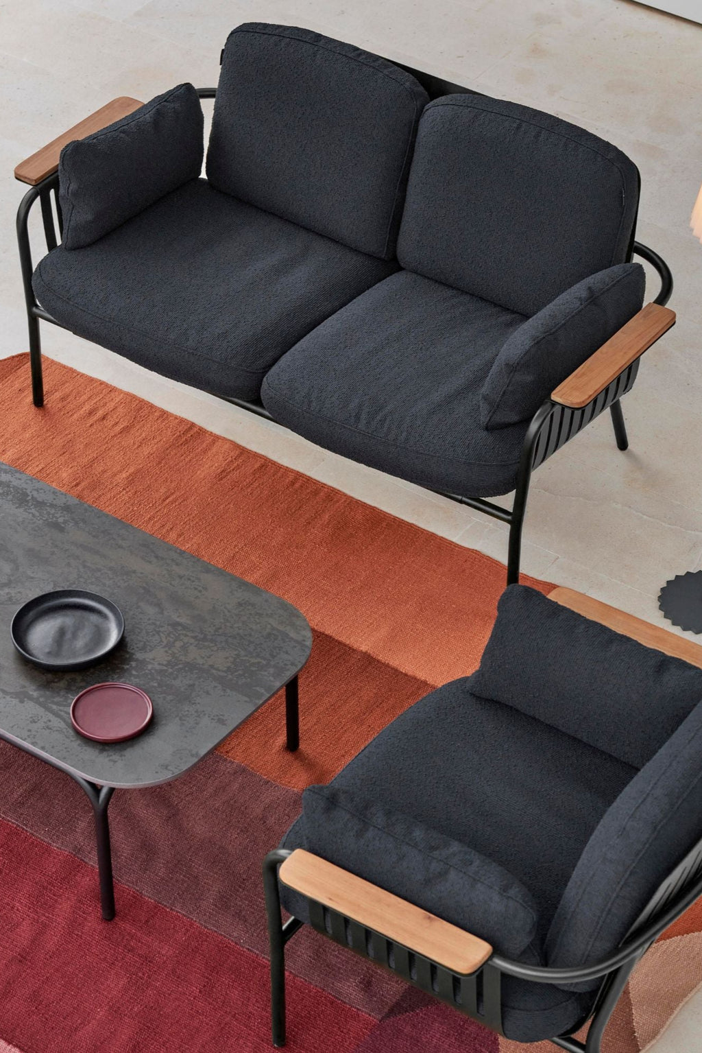 Gandia Blasco Capa 2-Seat Sofa, a modern outdoor sofa featuring a sleek matte black metal frame with elegant natural wood armrests and plush dark grey textured fabric cushions. This contemporary 2-seater is designed for comfortable outdoor lounge living, perfect for stylish patios, gardens, or balconies.