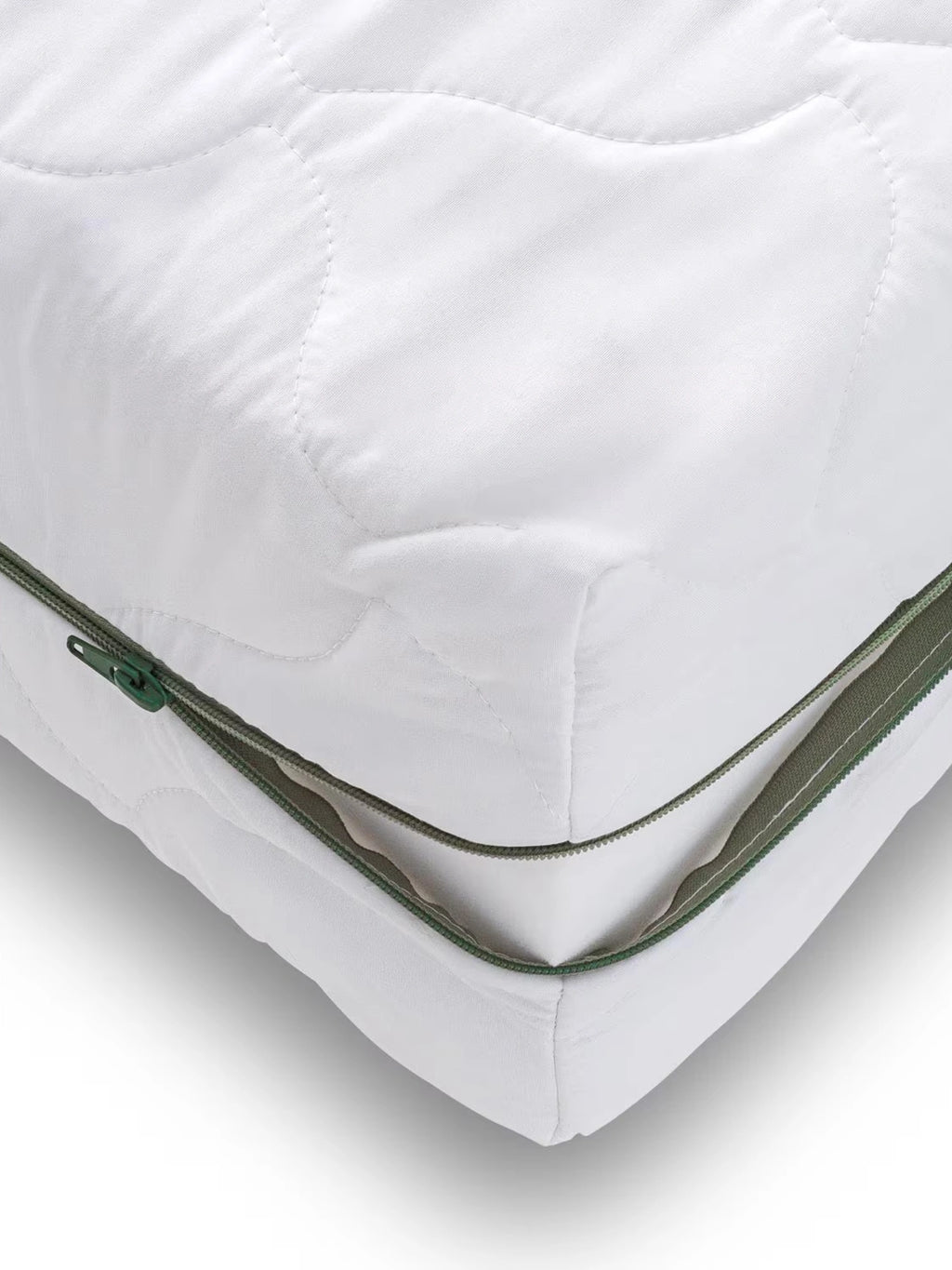 Mattress Comfort Mattress, a white quilted mattress protector featuring a soft, breathable fabric with a distinctive green zipper for easy removal and washing. This durable, zip-off mattress cover provides an extra layer of comfort and protection for any bed, ideal for maintaining a clean and hygienic sleeping environment in a bedroom.