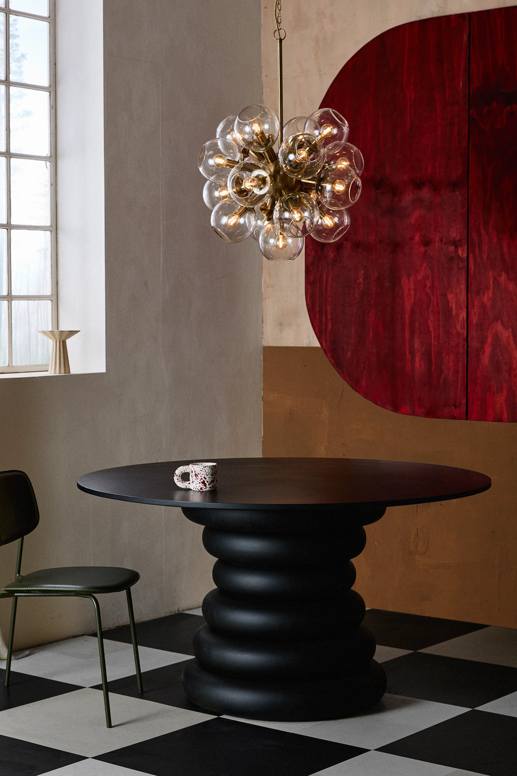 Nordal Yalu Dining Table, a striking matte black round dining table featuring a smooth, minimalist tabletop and a unique sculptural base composed of stacked, organic ring shapes.