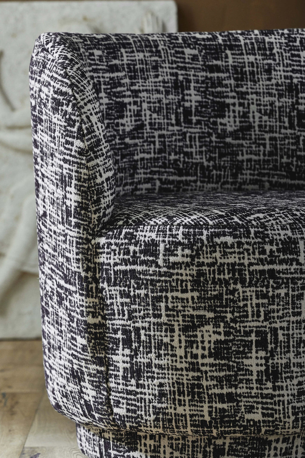 Nordal Bomu Lounge Chair, a contemporary armless lounge chair upholstered in a black and off-white textured fabric featuring an abstract grid pattern and a modern, curved silhouette. This sculptural accent chair offers plush comfort and a bold aesthetic with its unique weave. Perfect for modern minimalist living rooms or as a statement piece in contemporary interiors.