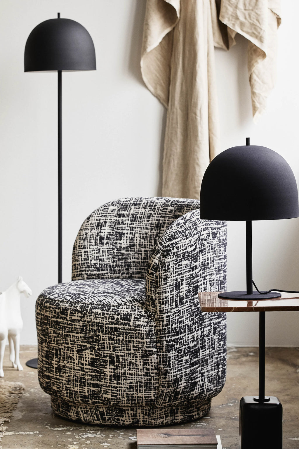 Nordal Bomu Lounge Chair, a contemporary upholstered armchair featuring a plush, rounded silhouette and a distinctive black and off-white textured fabric with a graphic, abstract weave. This modern barrel chair offers comfortable seating with its gently curved back and inviting design. Ideal as a stylish accent chair for a modern living room, cozy reading nook, or elegant bedroom.