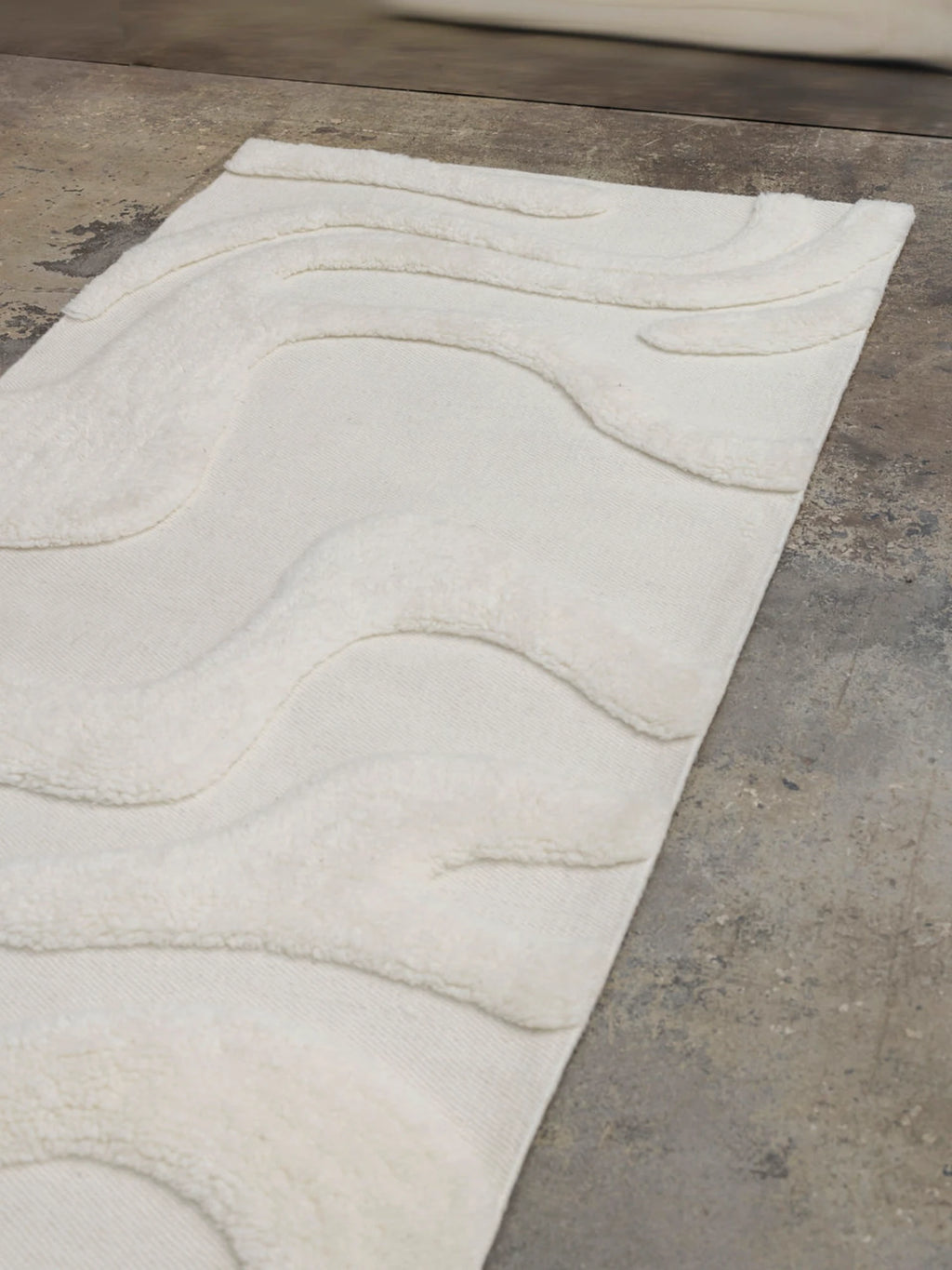 Tinted Objects Norlander Wool Runner Rug, a luxurious cream-colored rug featuring a thick, plush pile with raised wavy patterns over a flat-woven base, creating a modern textured design. This elegant wool runner is ideal for adding warmth and sophisticated style to hallways, entryways, or bedside areas for those seeking premium home decor.