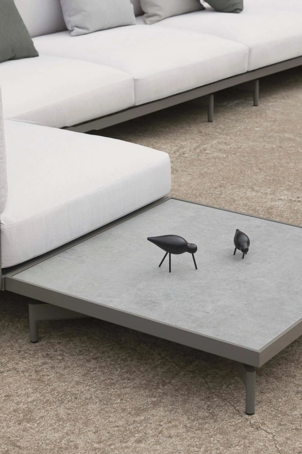 Gandia Blasco Onde Square Coffee Table, a modern minimalist outdoor coffee table featuring a sleek matte gray aluminum frame with clean lines and sturdy cylindrical legs. Its light gray, subtly textured square tabletop provides a contemporary concrete-like aesthetic, perfect for outdoor living. Ideal for contemporary patio setups, garden lounges, or minimalist outdoor entertaining spaces.