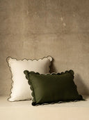 Two decorative pillows with scalloped edges, one white and one green, on a neutral background.