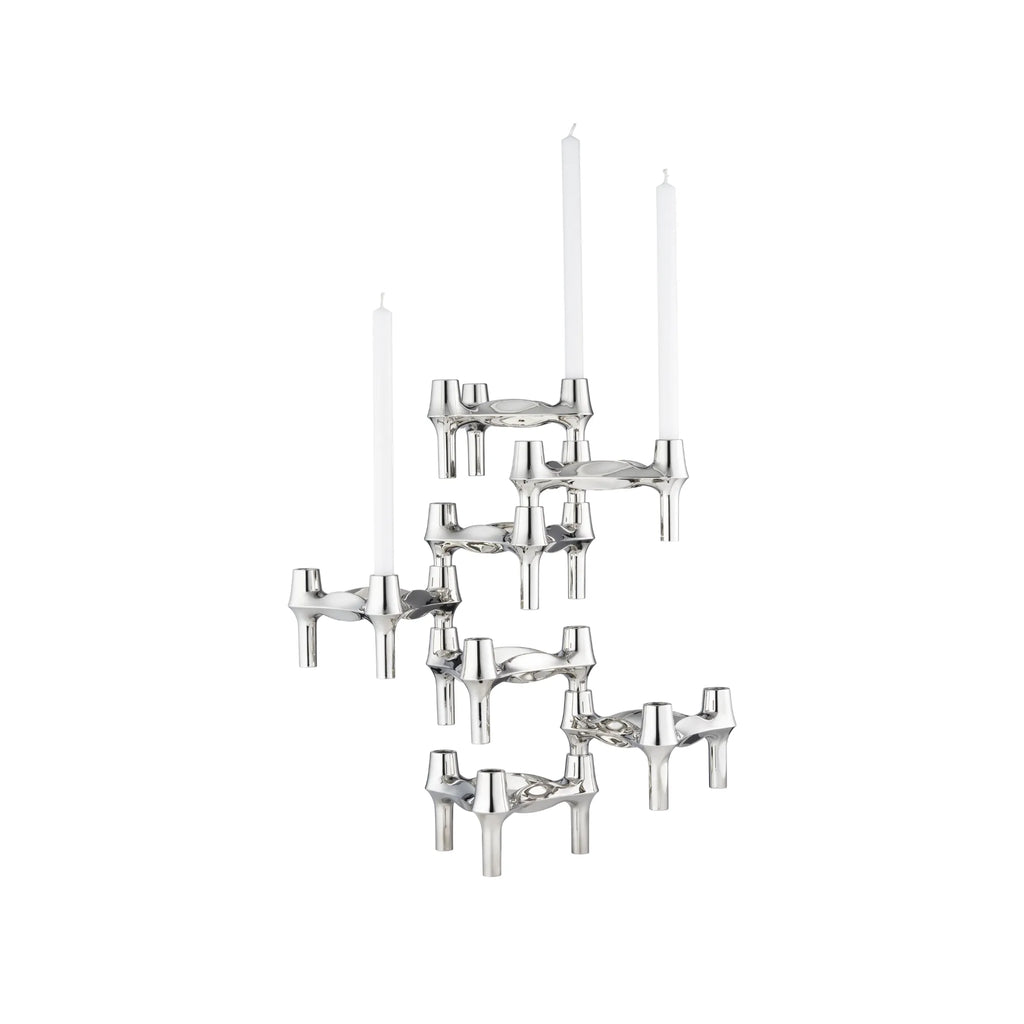 Stoff Nagel BMF Candle Holder - Configuration 2, a striking modular and sculptural candle holder system crafted from highly polished silver-toned metal. This iconic brutalist-inspired design features multiple interlocking three-legged units, artfully arranged to hold several white taper candles. It serves as a captivating mid-century modern centerpiece for dining tables, living room consoles, or contemporary shelf styling.