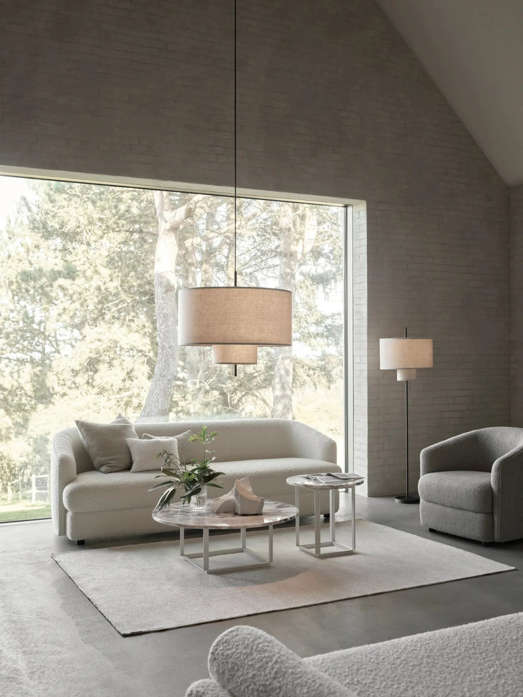 New Works Margin Pendant Lamp, shown as a layered, large and small beige fabric shade pendant light, suspended in a modern living room setting. This designer lighting adds premium, soft illumination.