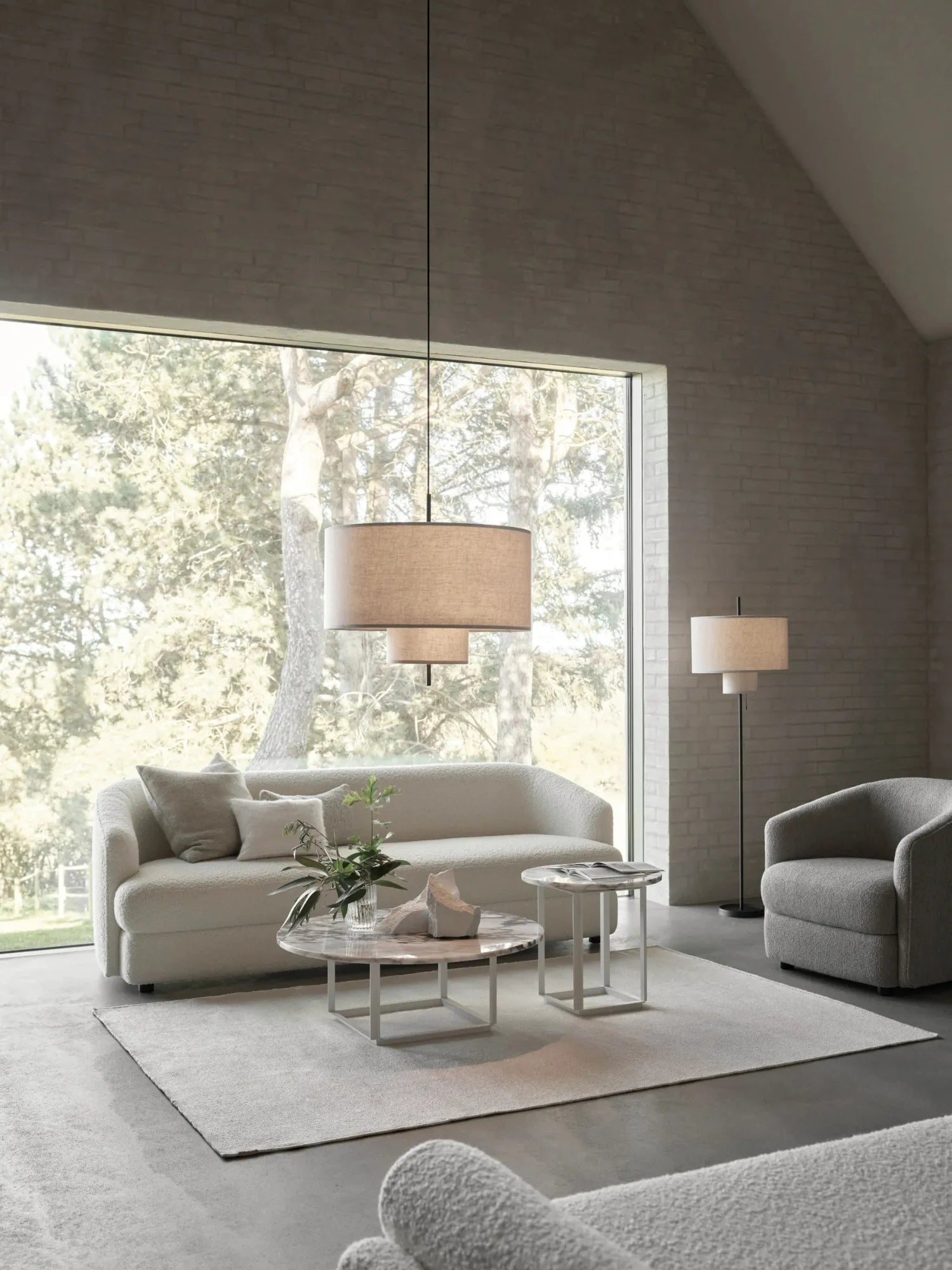 New Works Margin Pendant Lamp, shown as a layered, large and small beige fabric shade pendant light, suspended in a modern living room setting. This designer lighting adds premium, soft illumination.