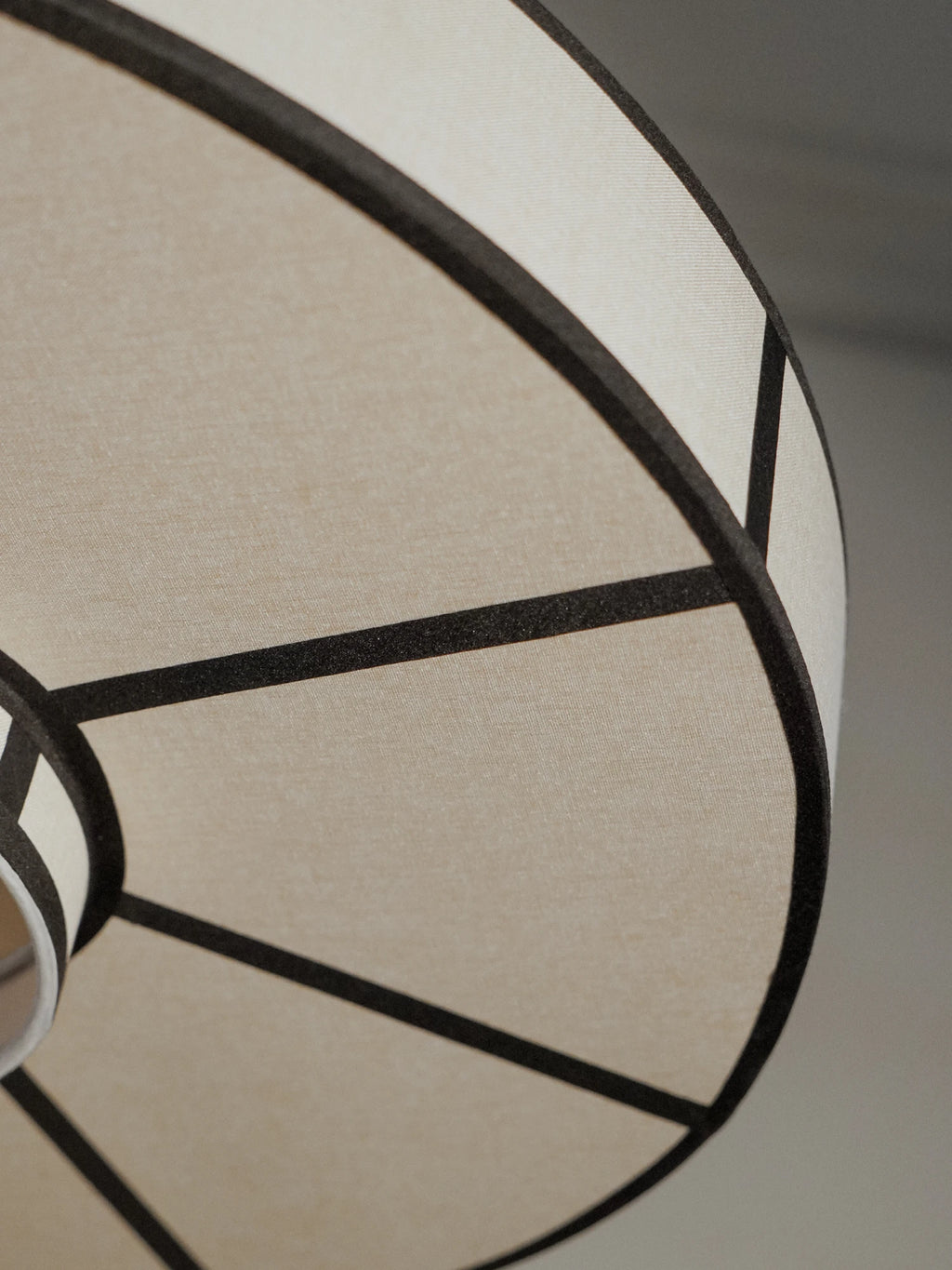 TAMO Aura Pendant Lamp 60, a modern geometric pendant light featuring a cream-colored fabric shade with a striking black metal frame forming a structured spherical design. This contemporary ceiling lamp offers minimalist style and soft illumination. Perfect for dining room lighting, living room accents, or modern entryways.