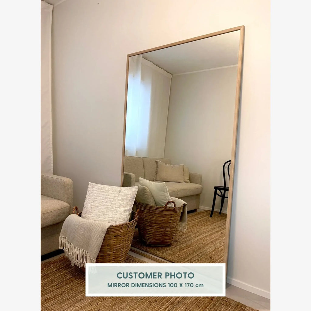 TCL Studios Sleek Full Length Mirror, a large rectangular mirror featuring a minimalist design with a slim natural light wood frame, offering a clean, contemporary aesthetic. This versatile floor mirror is perfect for adding depth and style to modern Scandinavian living rooms, bedrooms, or entryways.