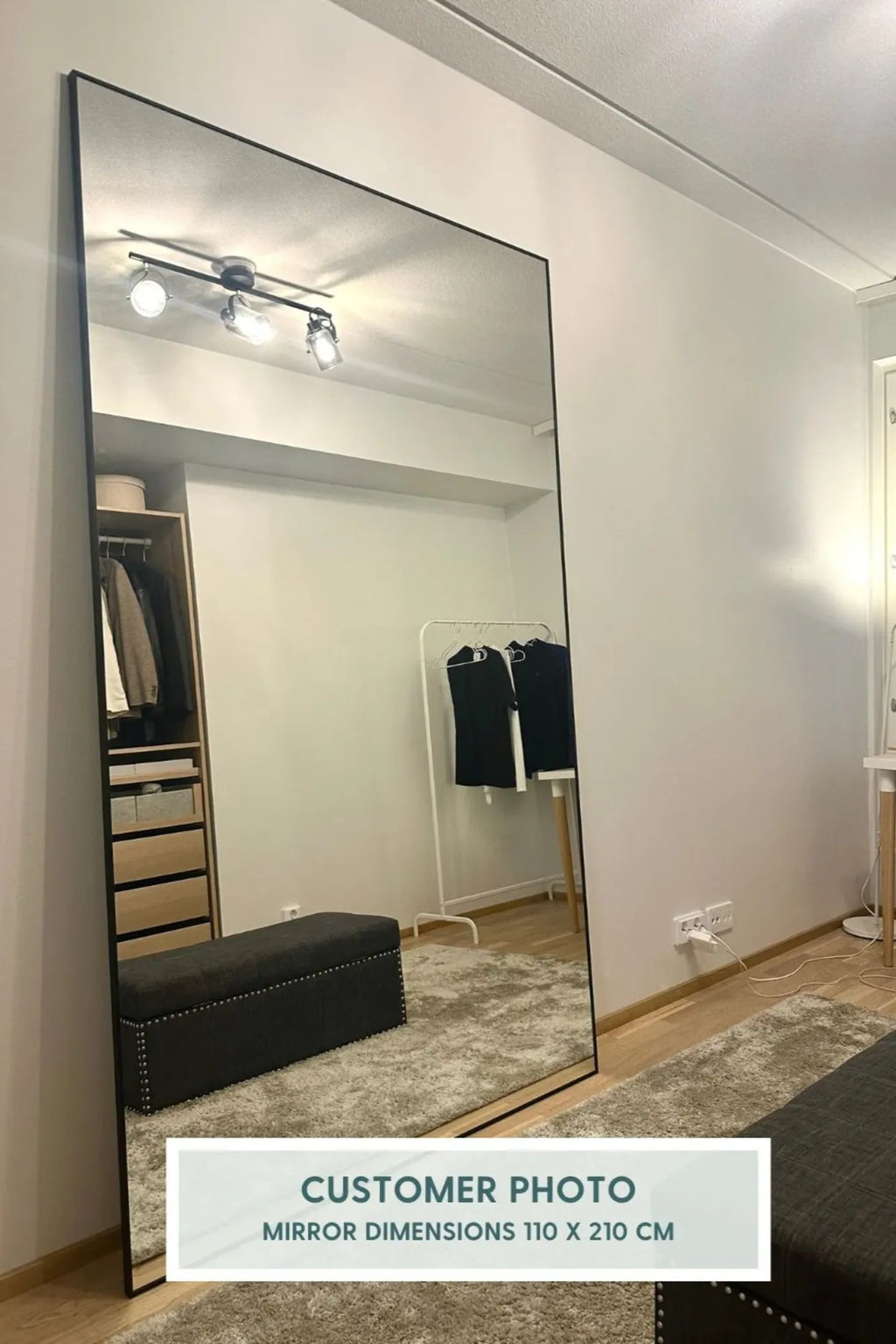 TCL Studios Sleek Full Length Mirror, a modern minimalist tall rectangular mirror featuring a slim black metal frame and a large reflective glass surface, designed to lean against a wall. This contemporary 110x210cm floor mirror is perfect as a functional dressing mirror for bedrooms, a stylish accent in entryways, or to expand space in living rooms with an industrial chic aesthetic.