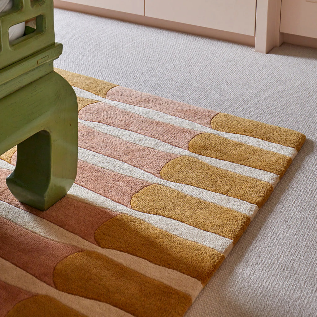 Layered Bamboo Forest Wool Rug, a luxurious modern area rug featuring a playful striped pattern in mustard yellow, blush pink, and cream white. Perfect for adding a soft, contemporary touch to any...