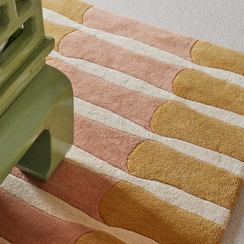Layered Bamboo Forest Wool Rug, a plush wool area rug with a bold geometric pattern in earthy tones of blush pink, mustard yellow, and cream. Perfect for adding a natural, modern accent to any livi...