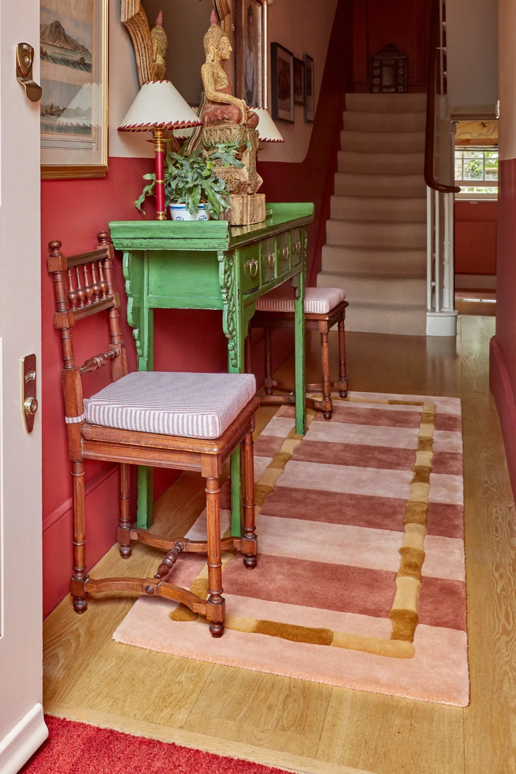 Layered Bamboo Stripe Wool Rug, a rectangular area rug featuring alternating shades of soft pink and terracotta stripes with a tan bamboo-inspired border. Perfect for adding warmth and sophisticate...