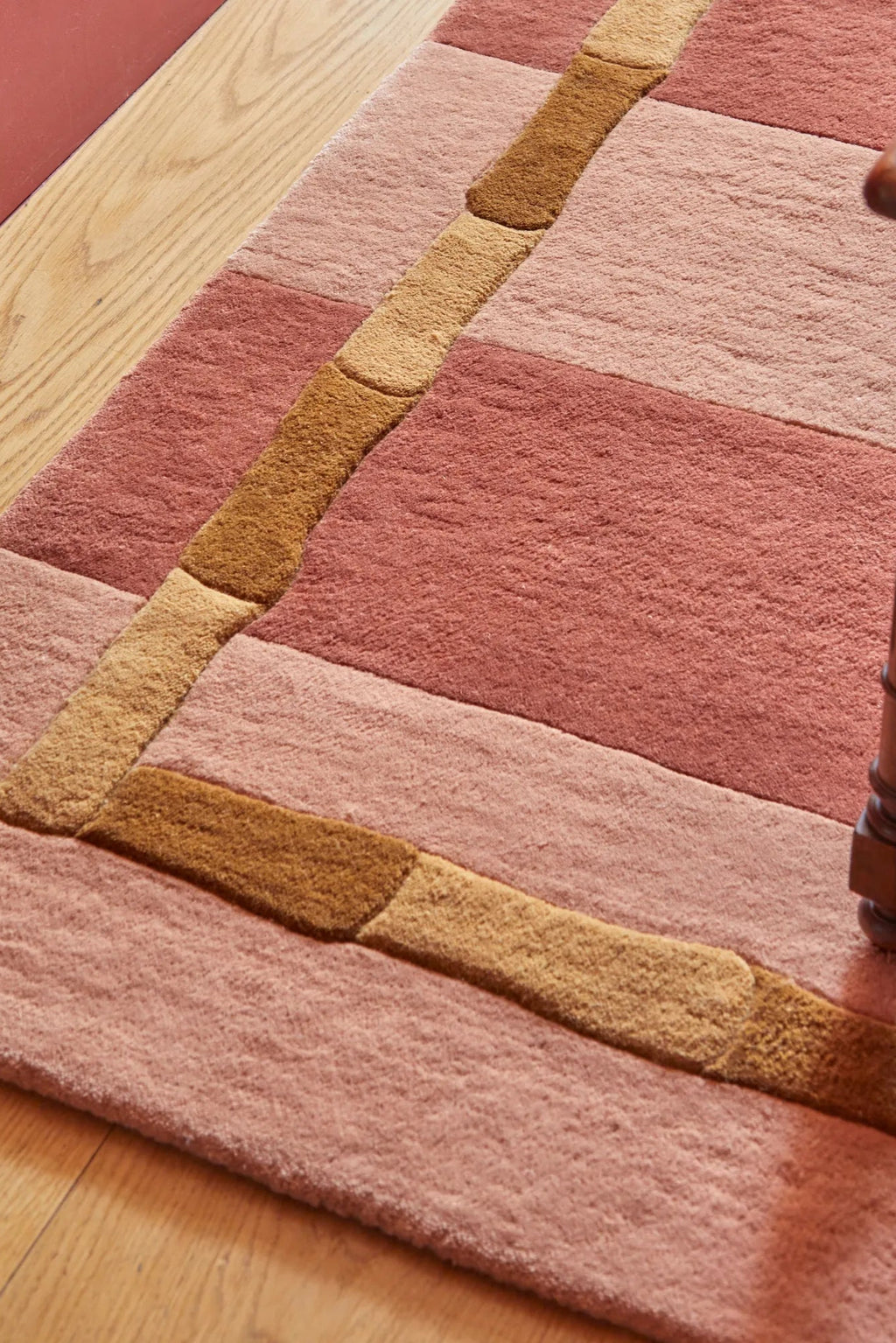 Layered Bamboo Stripe Wool Rug, featuring a cozy blend of pink and terracotta hues with raised brown and tan bamboo-like stripes. This soft, textured wool rug adds warmth and style to any living sp...