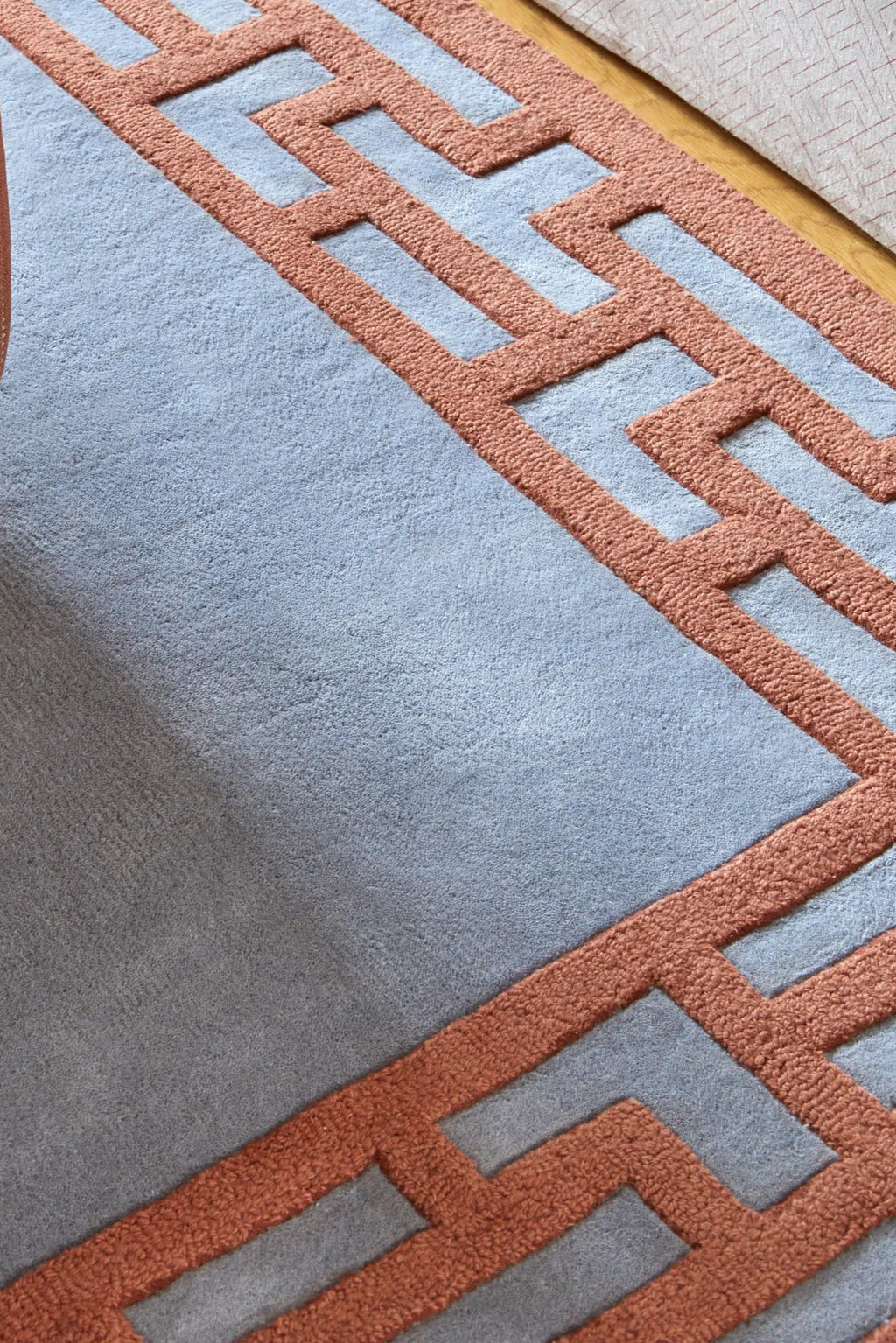 Layered Indocine Wool Rug, a luxurious light blue and terracotta geometric pattern area rug crafted from soft wool. Perfect for adding a modern statement piece to living rooms and dining areas.