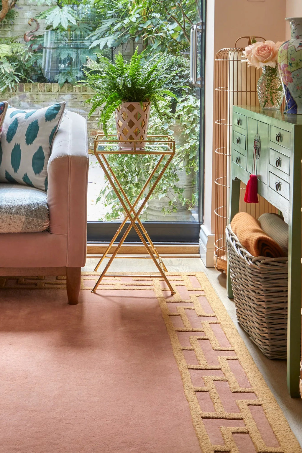 Layered Indocine Wool Rug, a luxurious blush pink area rug with a contrasting gold geometric border design. This stylish wool runner adds warmth and texture to any modern living space or hallway.