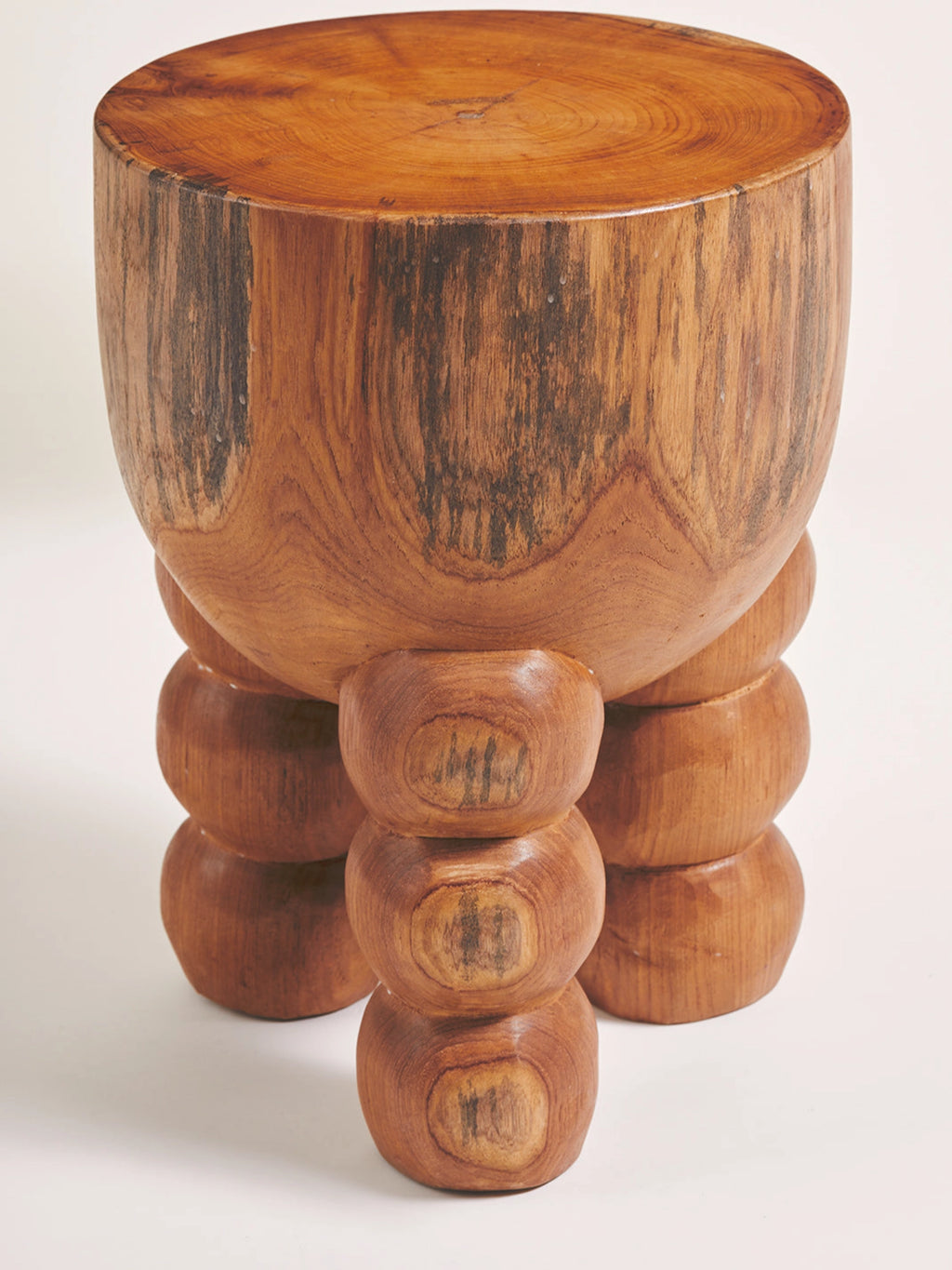 Heaps & Woods Alice Stool, a sculptural organic modern stool crafted from solid teak wood with a warm medium brown finish and visible natural wood grain.