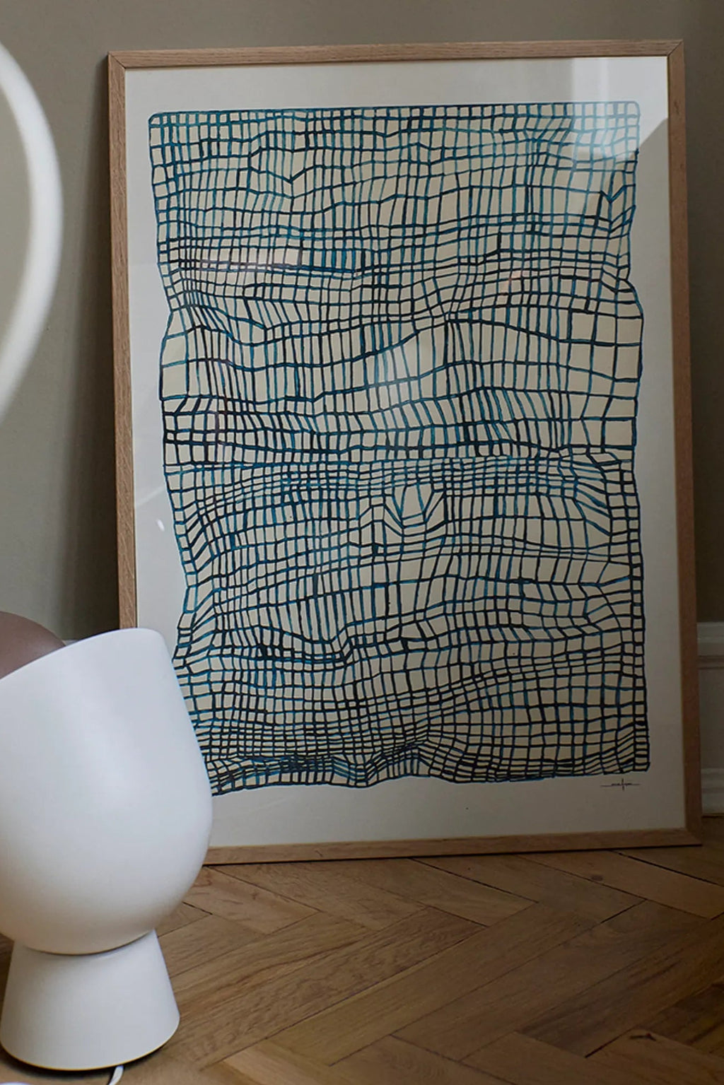 The Poster Club Sketchbook, an abstract graphic art print featuring a dynamic, distorted wavy grid pattern in deep teal and blue-green hues on a neutral cream background, presented in a light natural oak frame. This contemporary poster is an ideal choice for minimalist living rooms, Scandinavian bedrooms, or as a striking piece of modern gallery wall art.